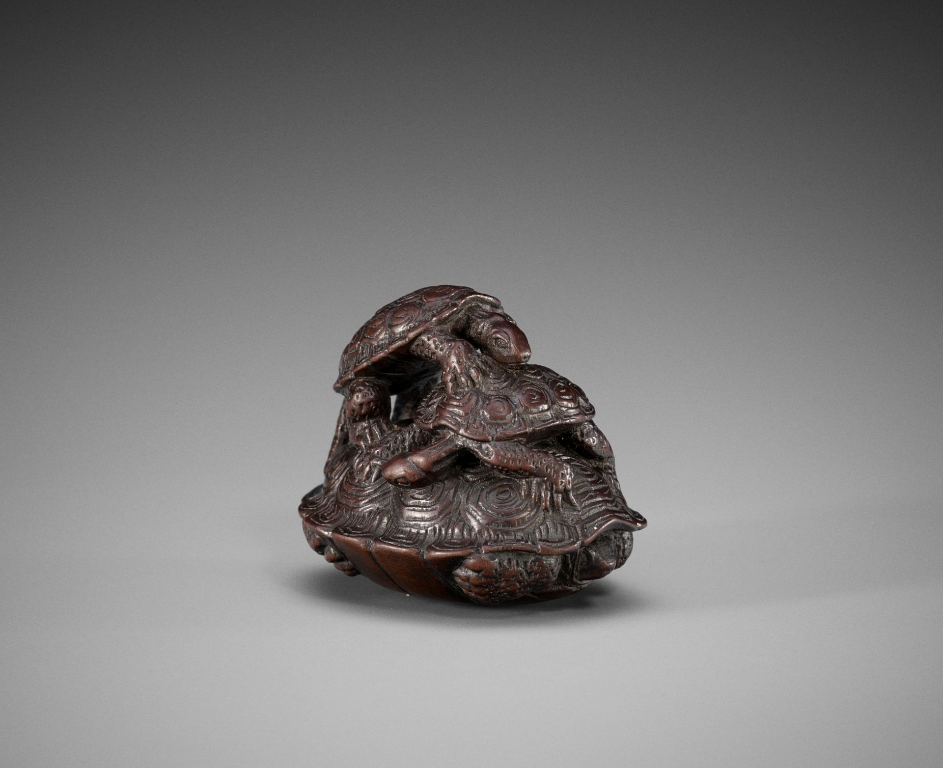 A WOOD NETSUKE OF A THREE TURTLES IN A PYRAMID