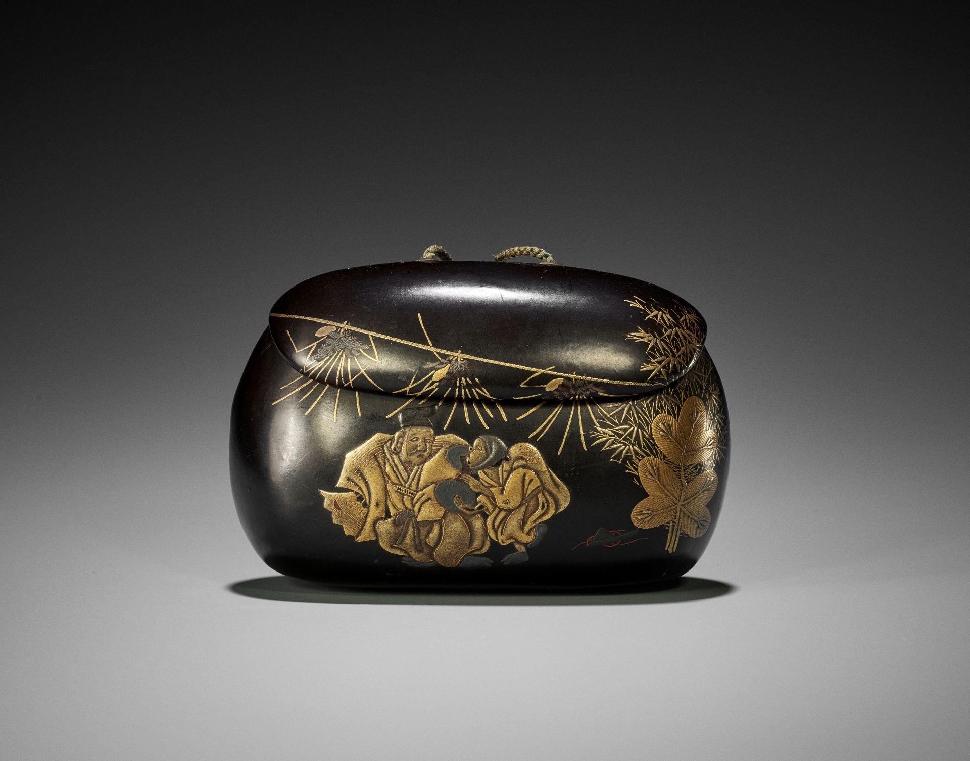 A RARE BLACK AND GOLD LACQUER TONKOTSU DEPICTING A NEW YEAR'S SCENE