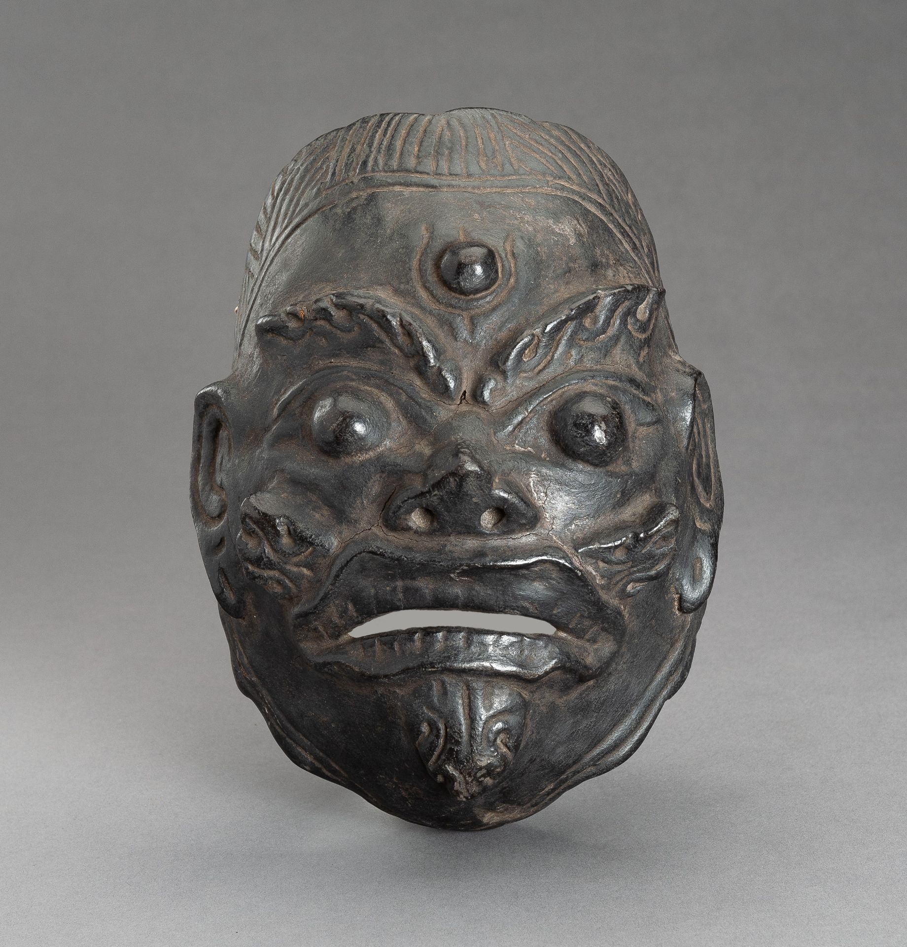 A BLACK LACQUERED WOOD MASK OF WRATHFUL DEITY