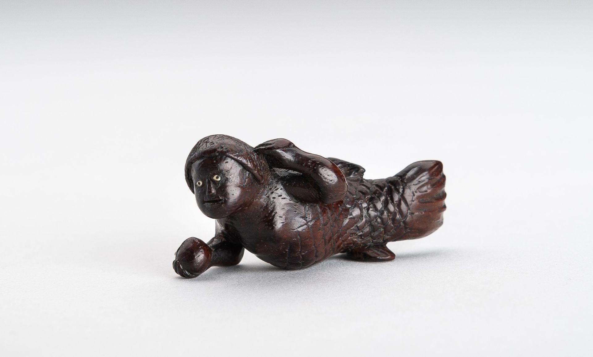 A WOOD NETSUKE OF A SWIMMING NINGYO (MERMAID)