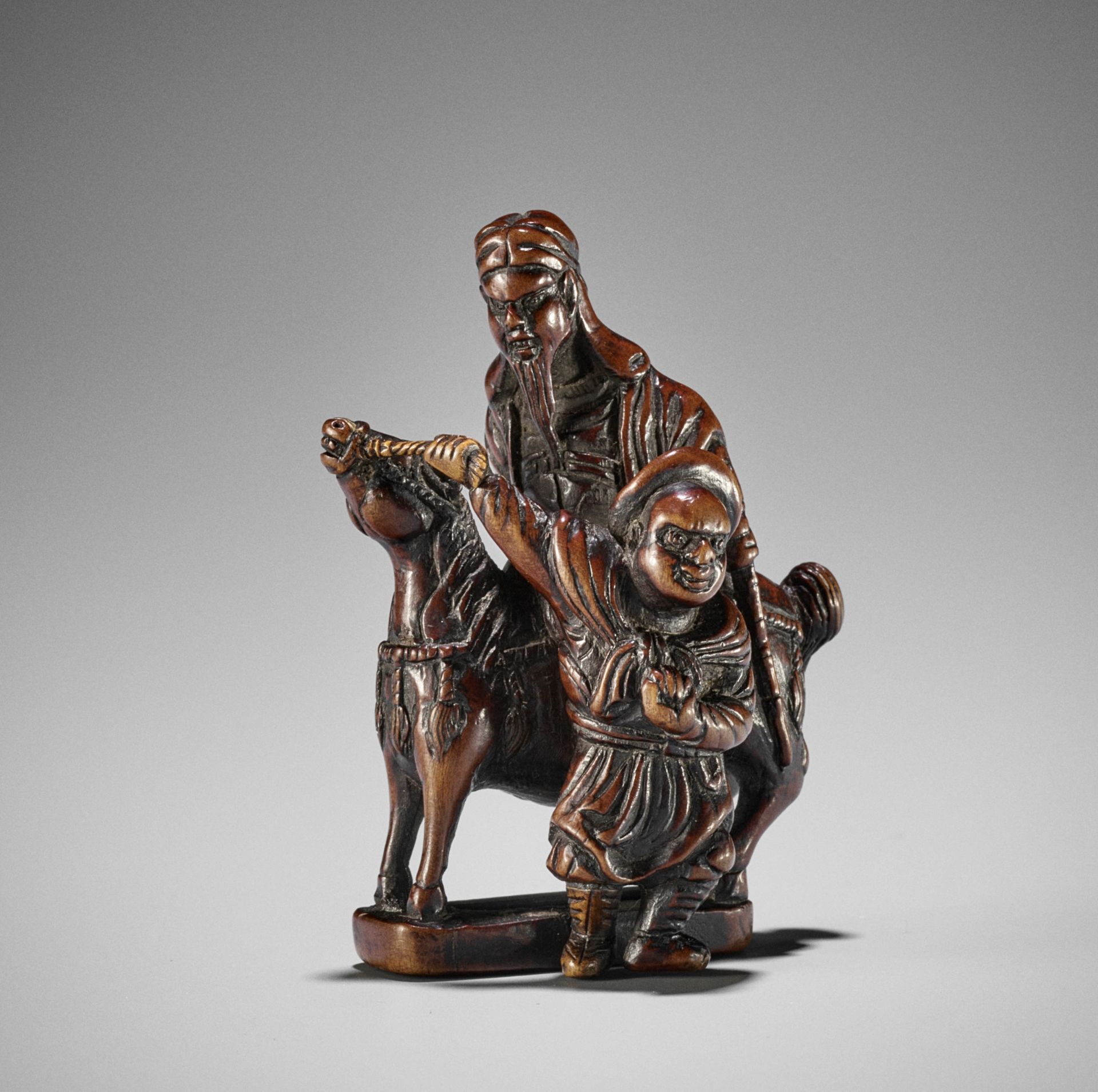 A LARGE AND POWERFUL BOXWOOD NETSUKE OF KAN'U WITH ATTENDANT