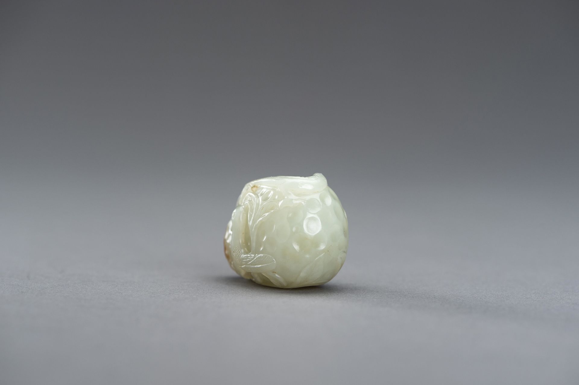 A CELADON JADE PENDANT OF A LYCHEE WITH BIRDS, 1920s - Image 8 of 9