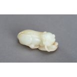 A WHITE AND RUSSET JADE PENDANT OF A BUDDHIST LION, QING DYNASTY