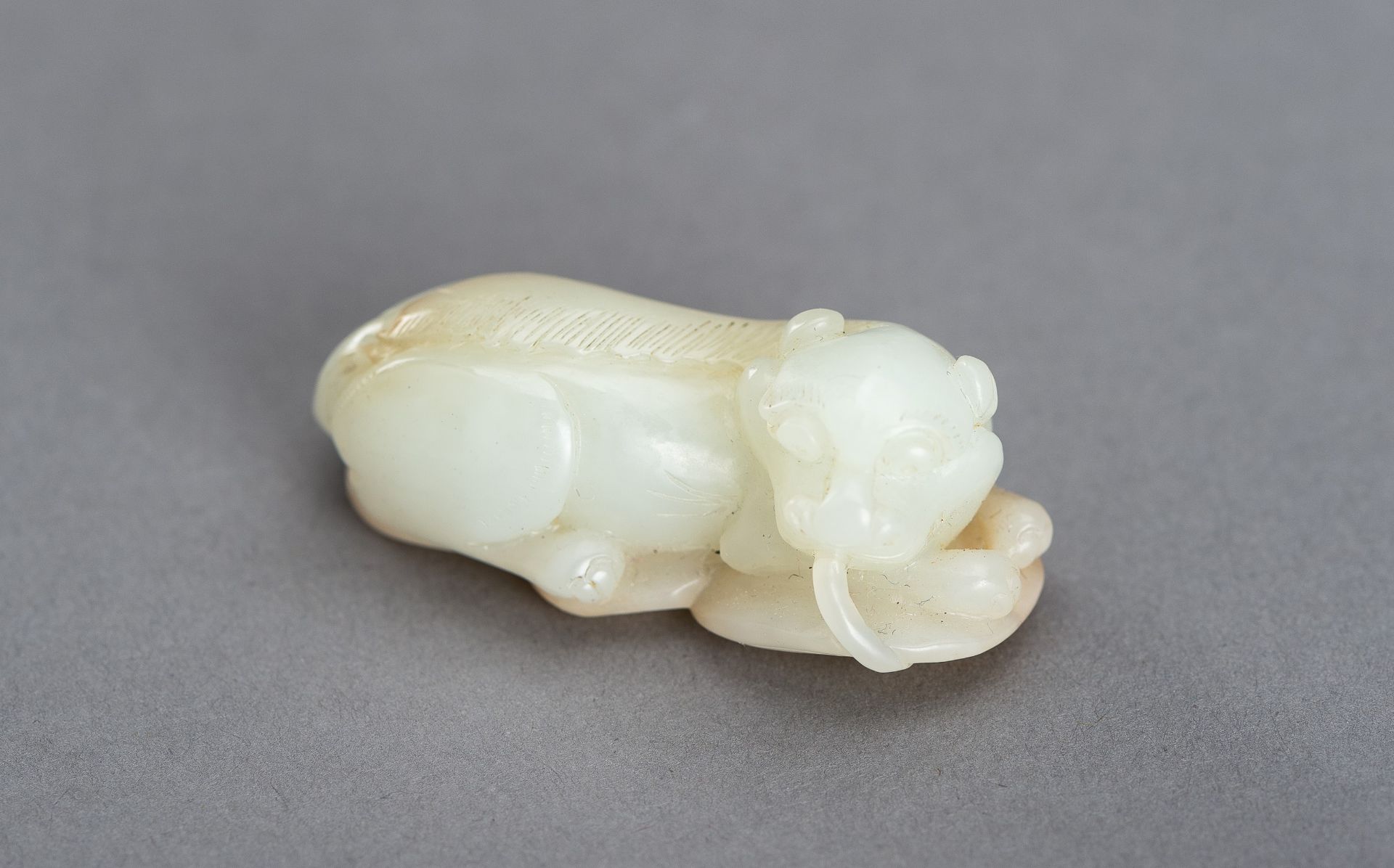 A WHITE AND RUSSET JADE PENDANT OF A BUDDHIST LION, QING DYNASTY