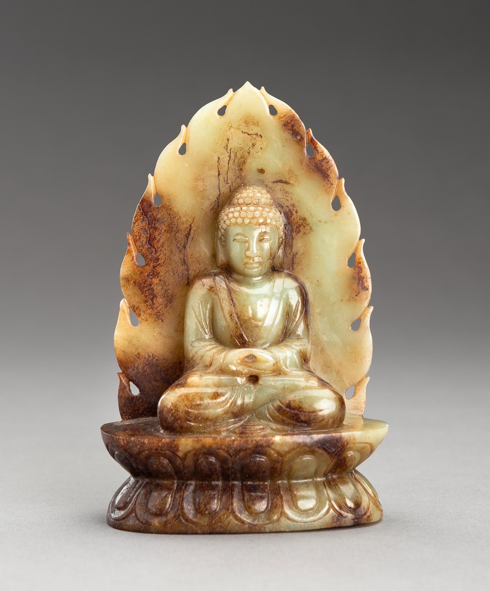 A PALE CELADON AND RUSSET JADE FIGURE OF BUDDHA