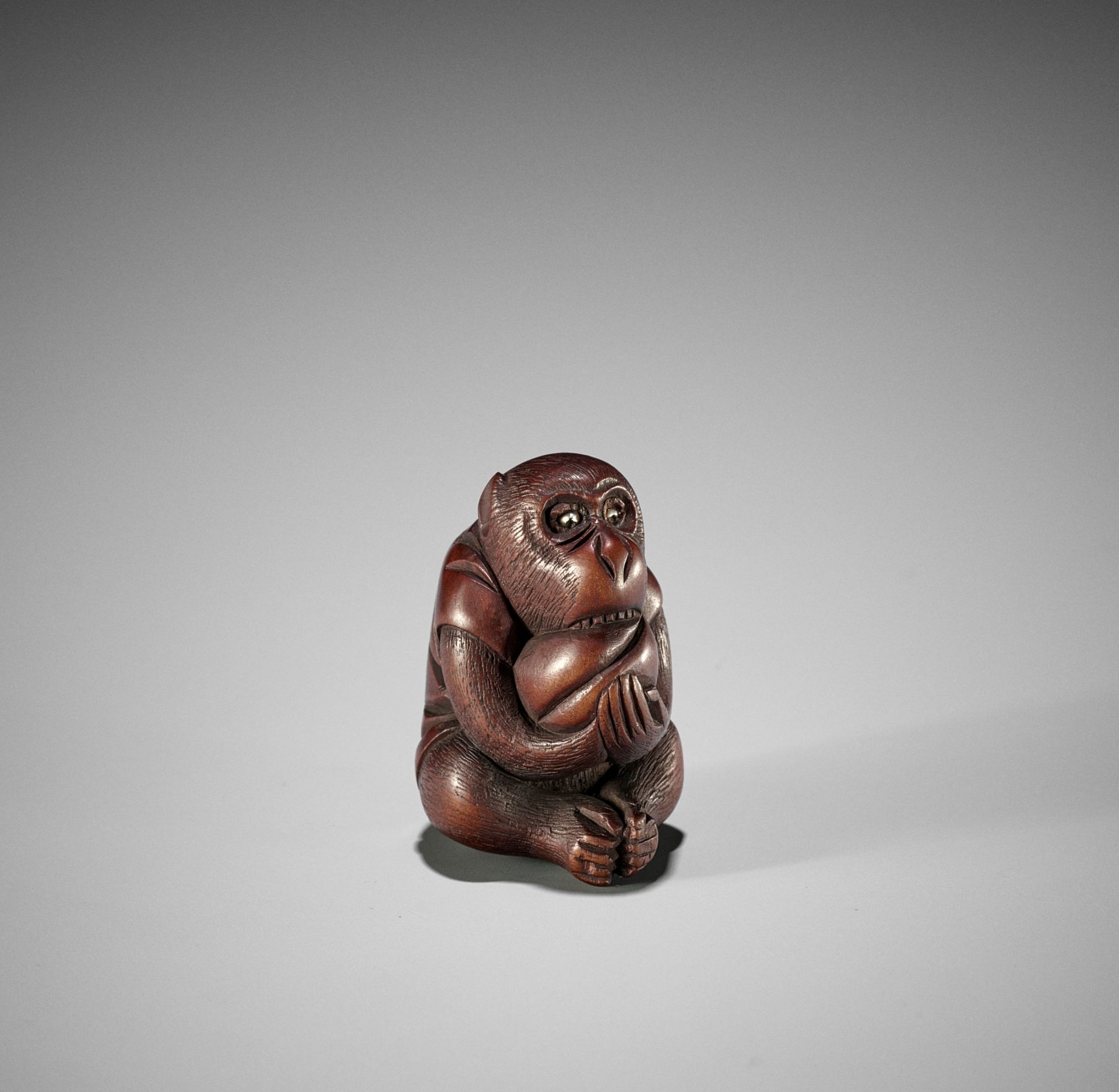 MASAKAZU: A WOOD NETSUKE OF A MONKEY WITH PEACH, SCHOOL OF TOMOKAZU