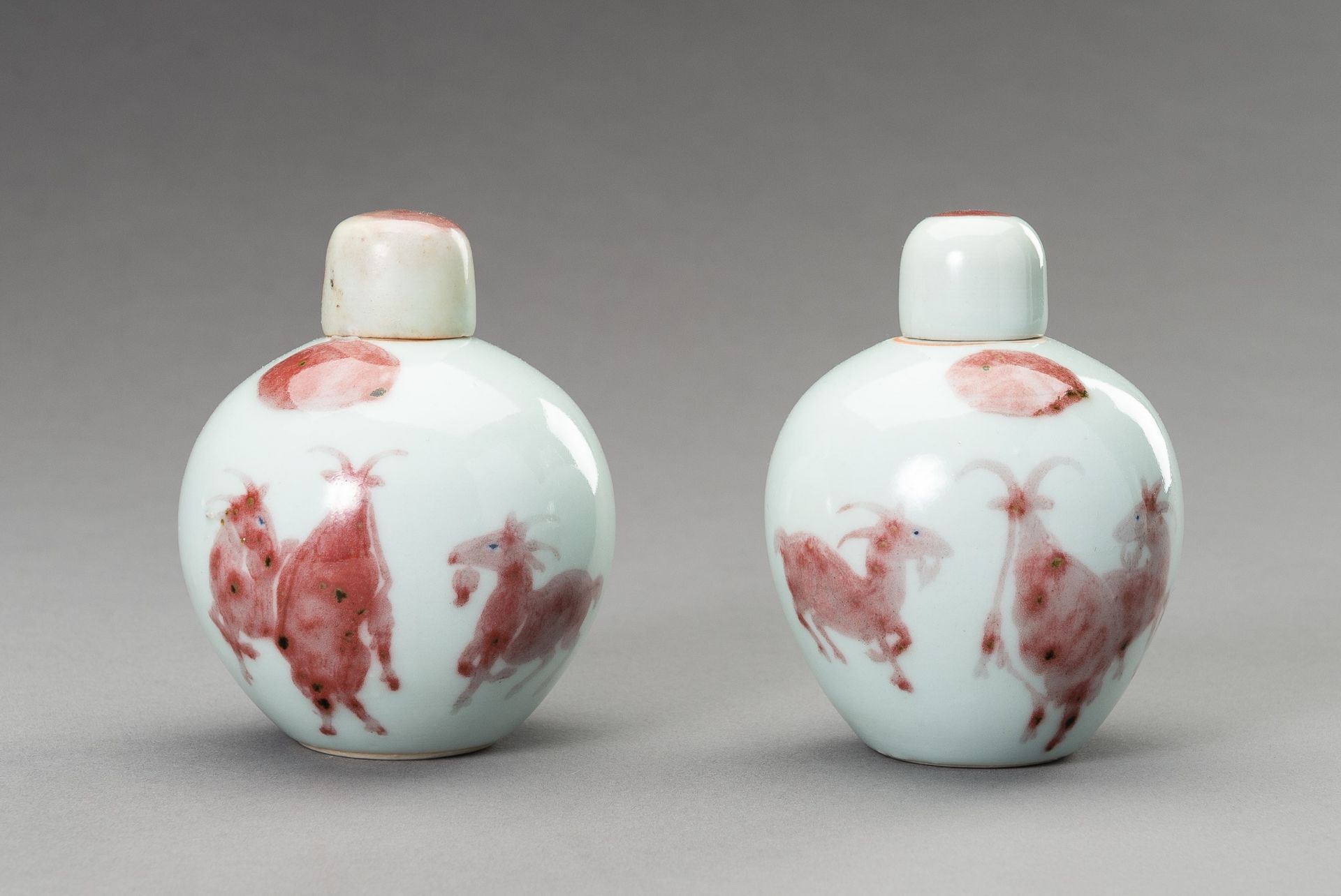 A RARE PAIR OF COPPER-RED, LIDDED PORCELAIN JARLETS DEPICTING GOATS, 1900s