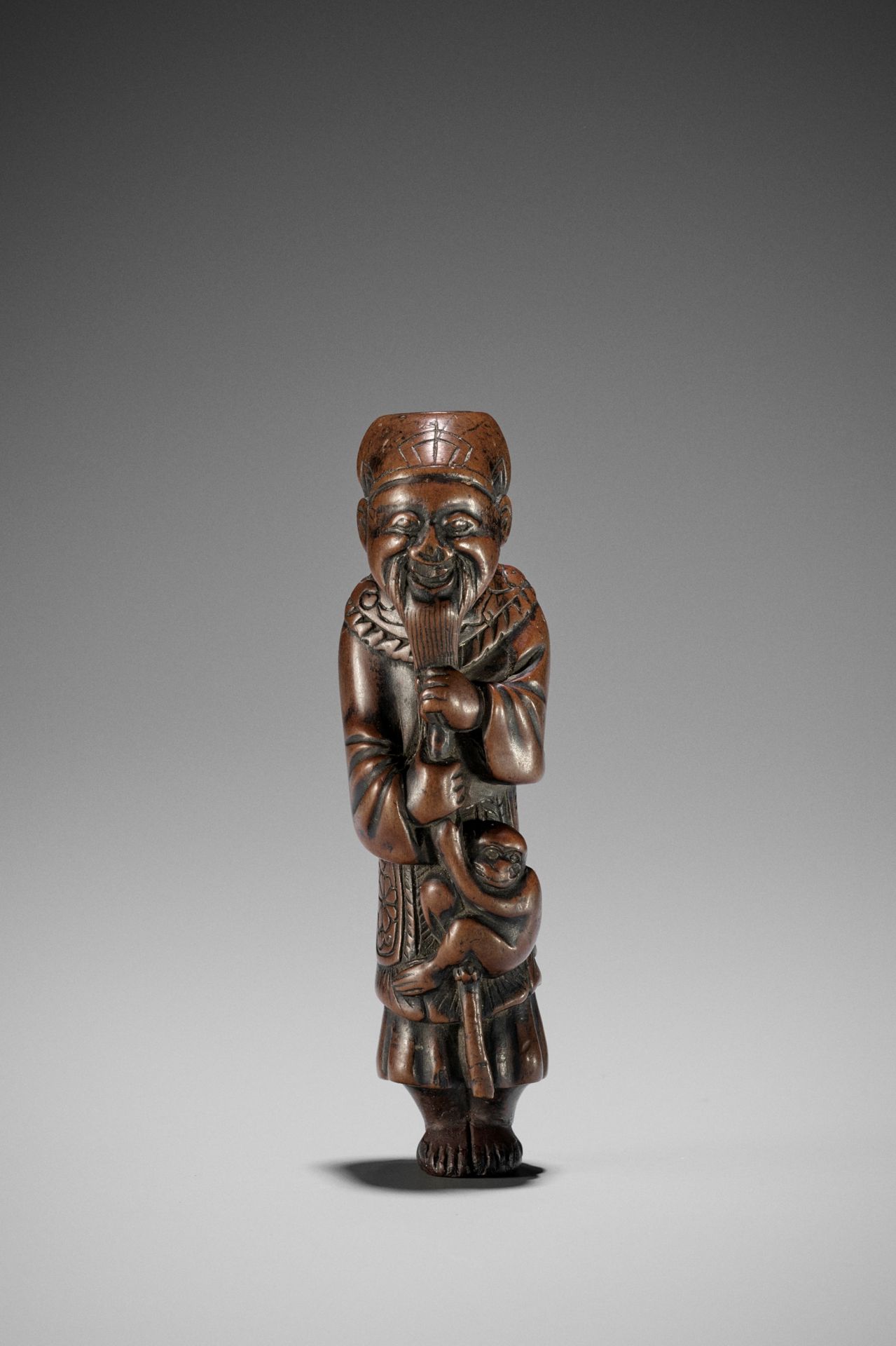 AN UNUSUAL WOOD NETSUKE OF A CHINESE SARUMAWASHI (MONKEY TRAINER)