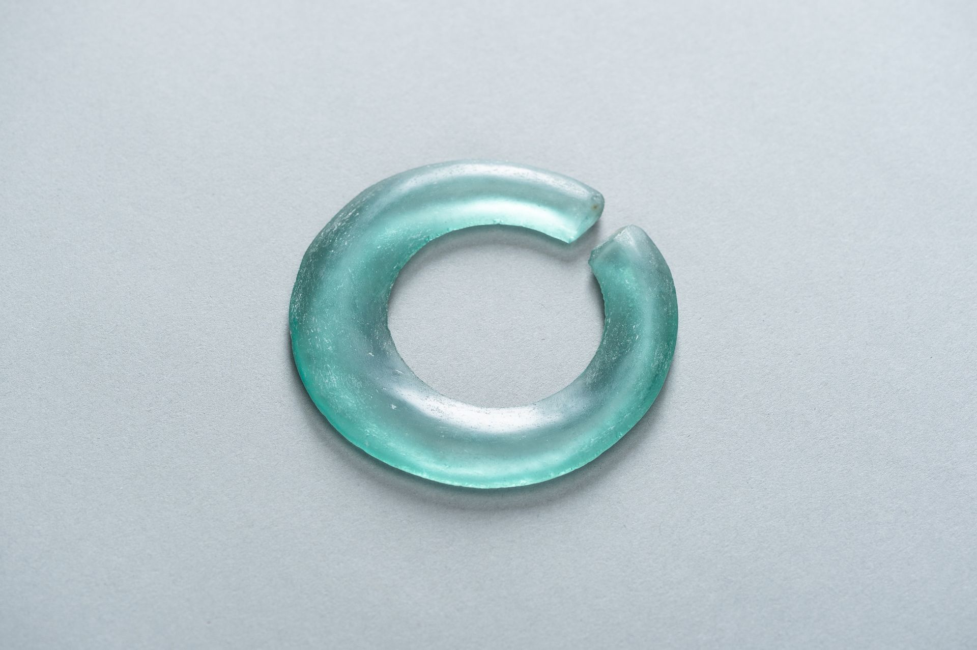 AN ARCHAIC PALE GREEN GLASS DISC