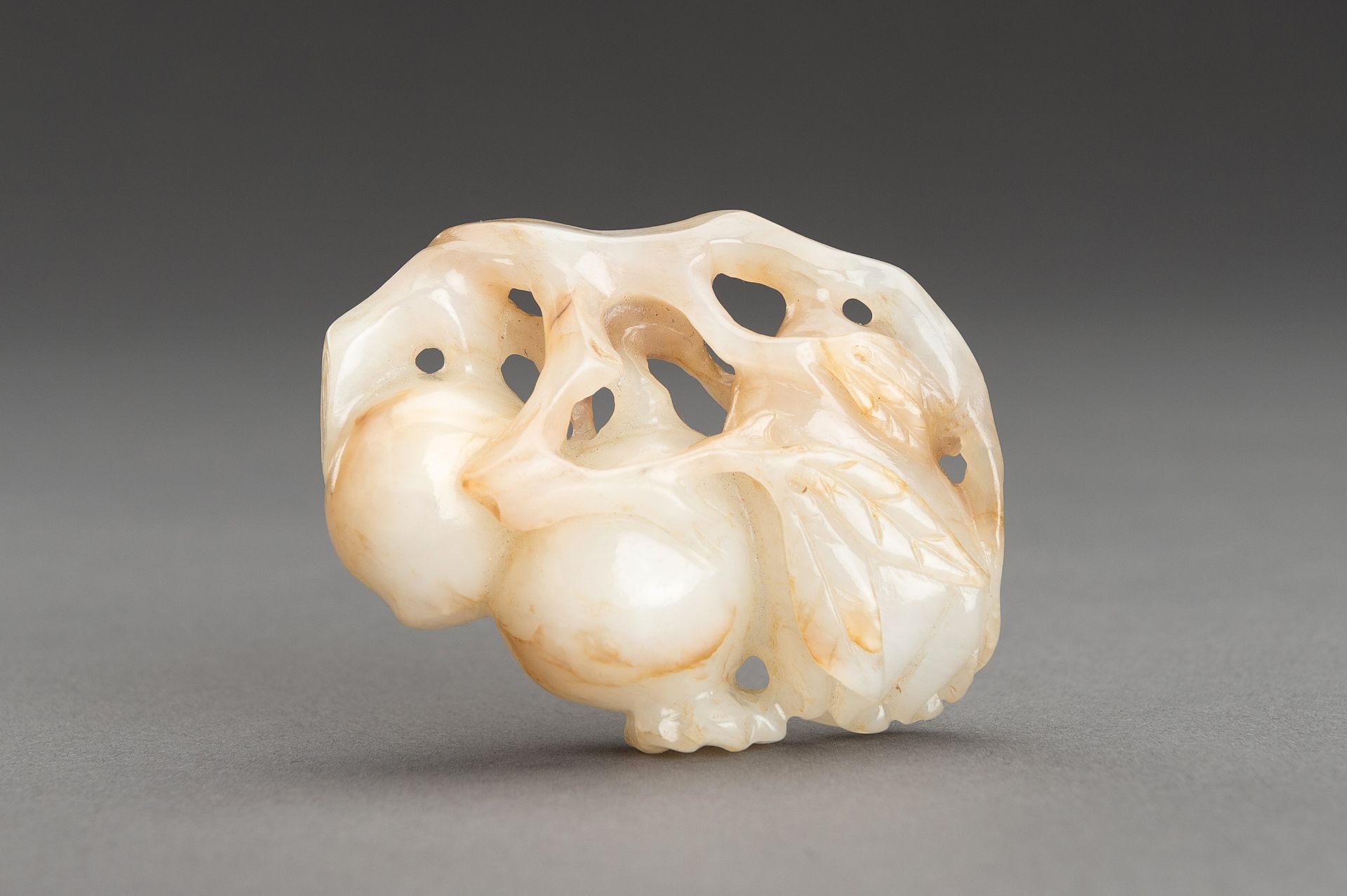 A WHITE AND RUSSET JADE 'THREE AUSPICIOUS FRUITS' PENDANT