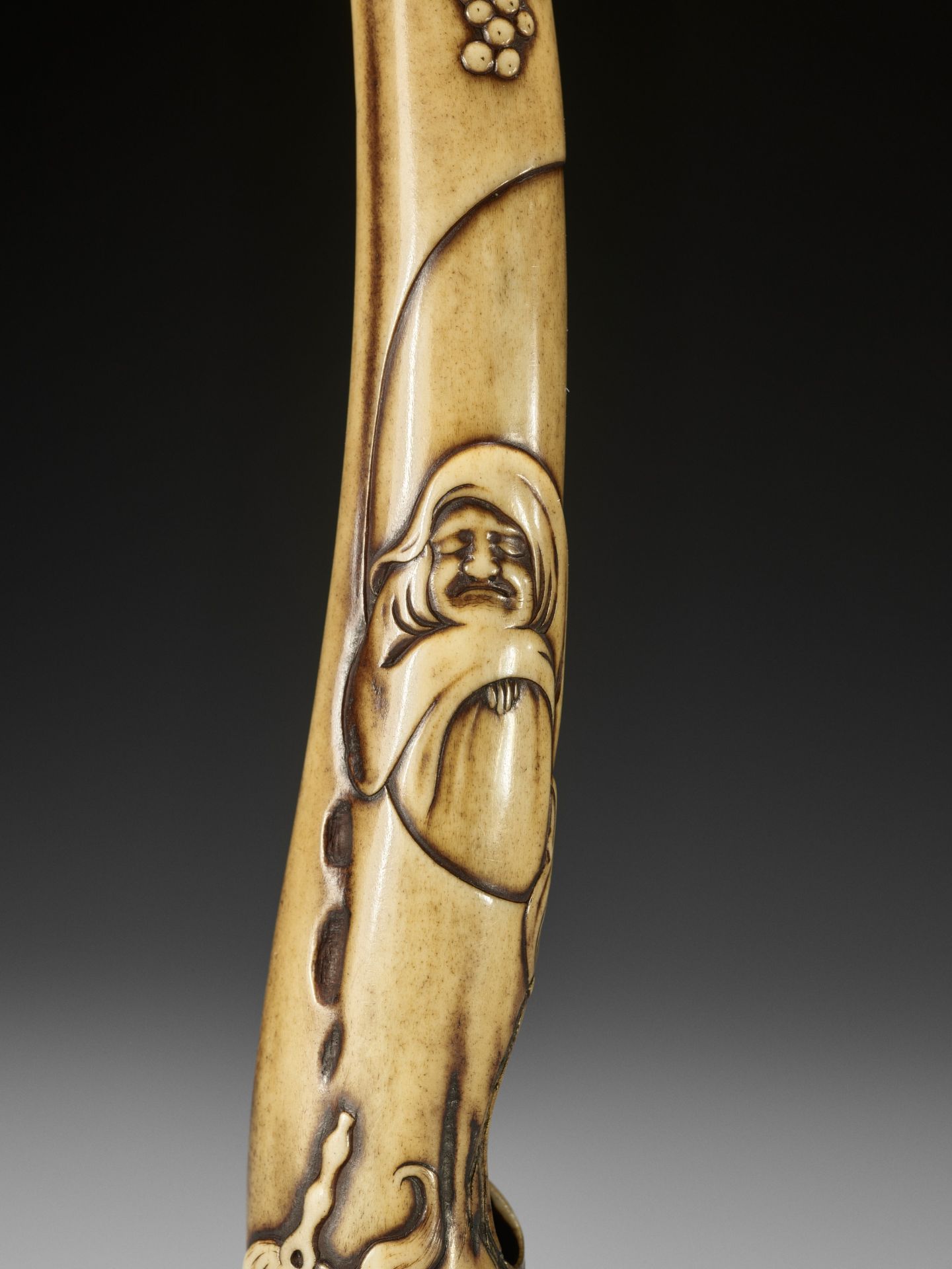 SOKEI: A FINE STAG ANTLER KISERUZUTSU WITH DARUMA, GRAPEVINE AND HOSSU