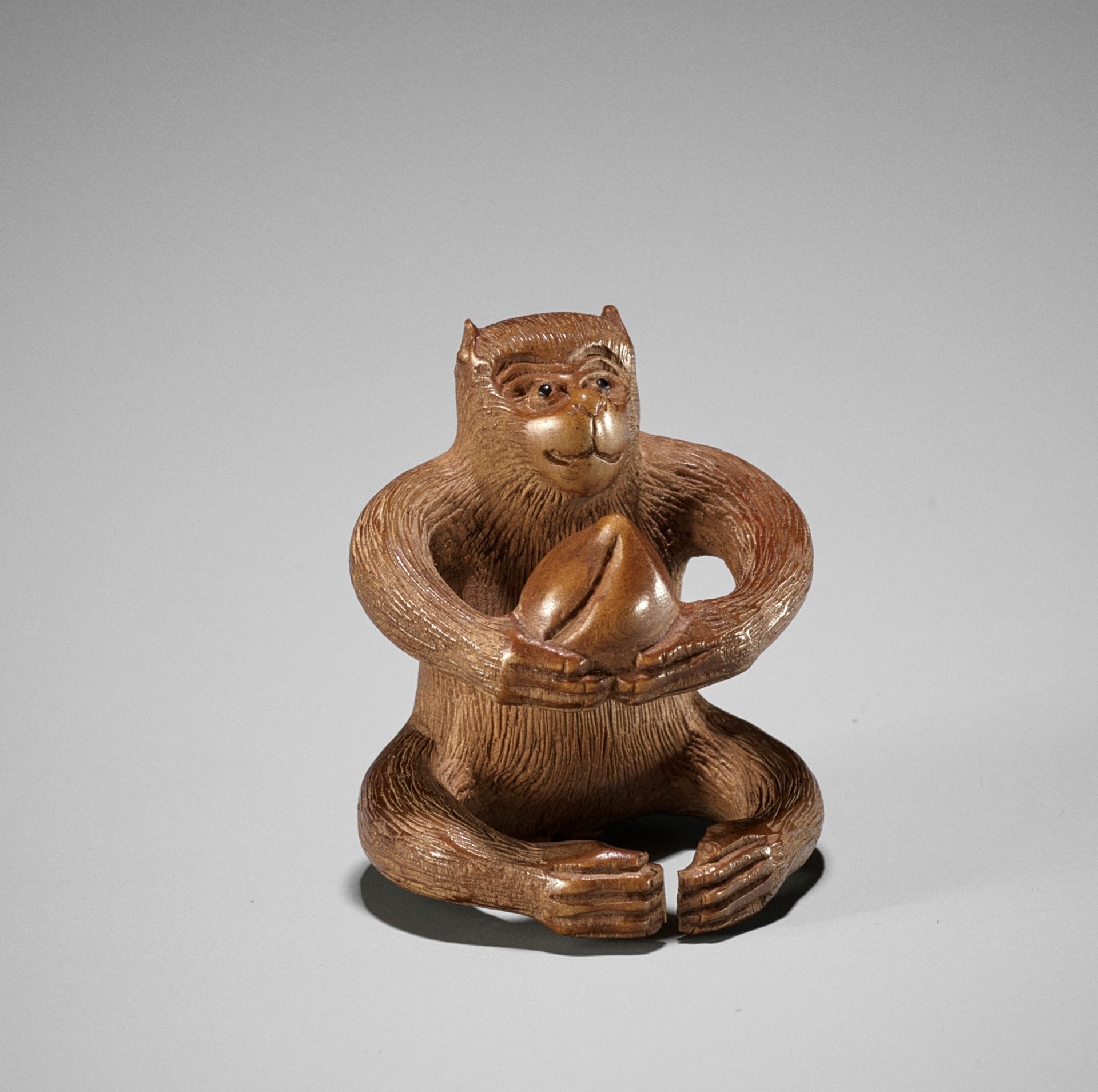 AN AMUSING WOOD NETSUKE OF A MONKEY WITH PEACH