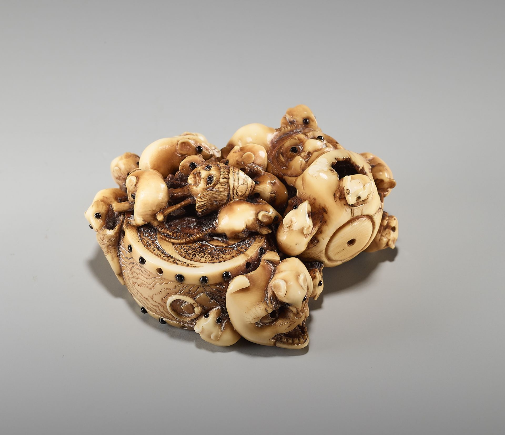 A CHARMING AND RARE IVORY NETSUKE OF A BUNDLE OF RATS WITH DARUMA DOLLS AND MASKS BY MASAMITSU