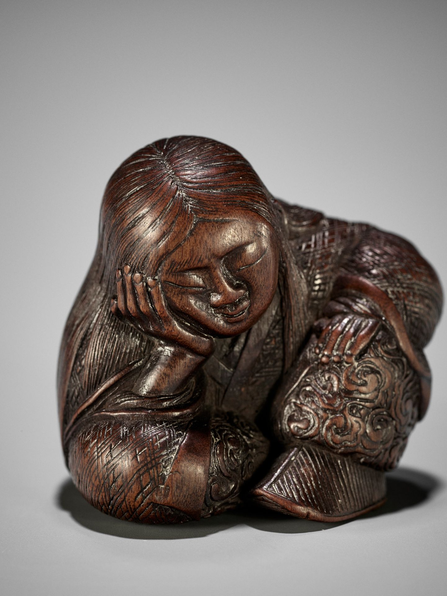 TADATOSHI: A SUPERB NAGOYA SCHOOL WOOD NETSUKE OF A SEATED SLEEPING SHOJO