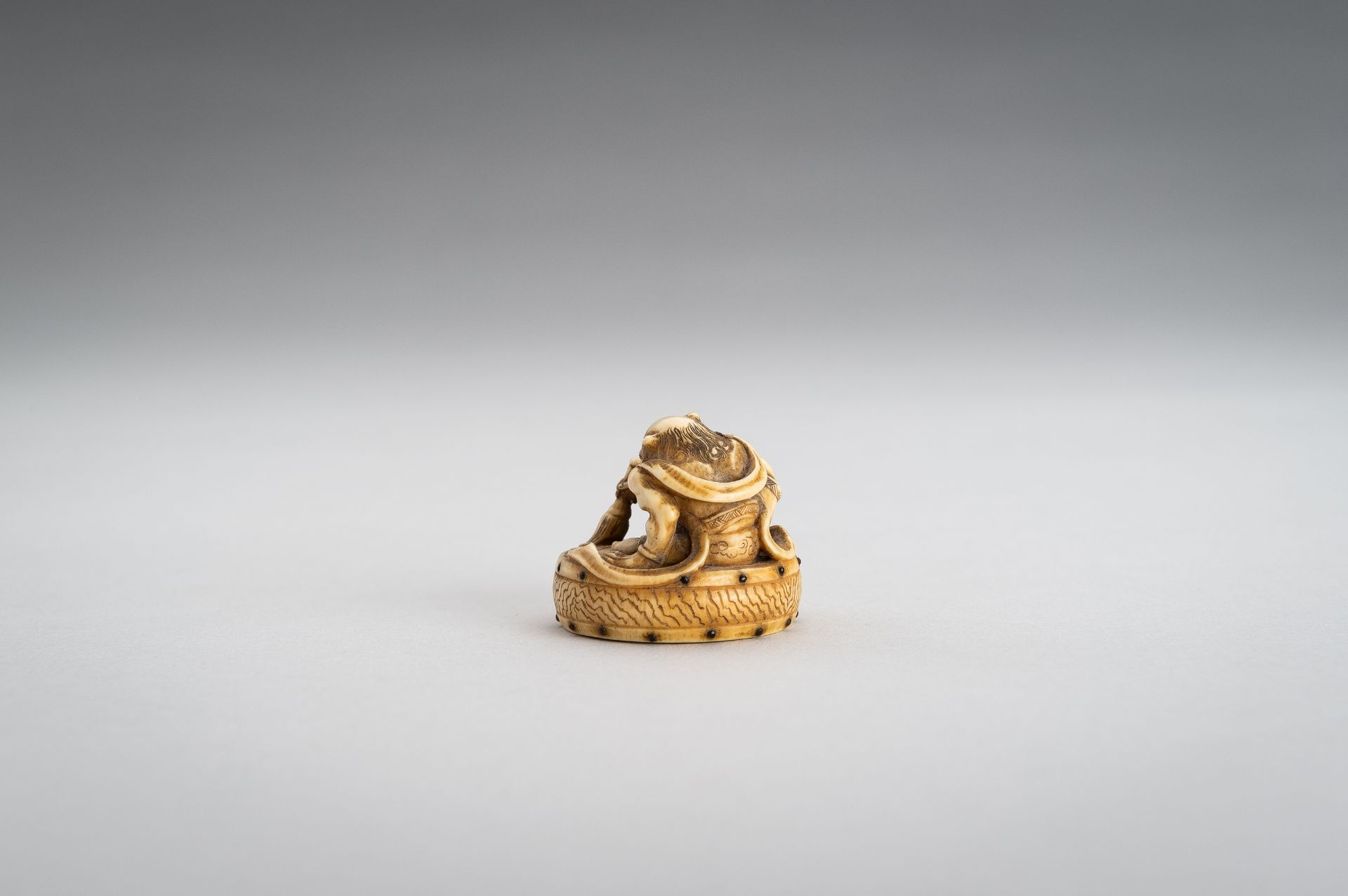 GYOKUSHU: AN IVORY NETSUKE OF AN ONI CLEANING A DRUM - Image 9 of 12