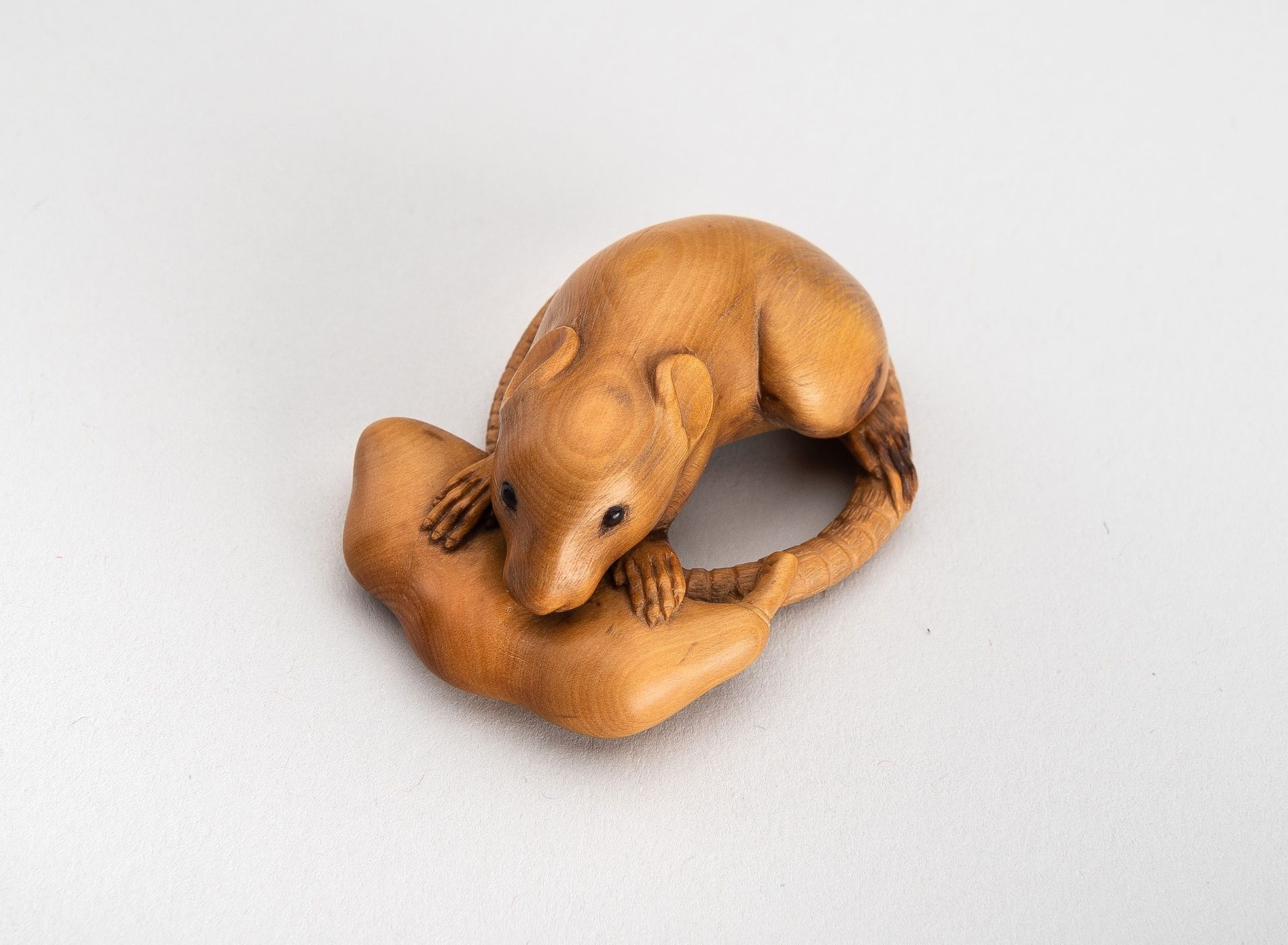 A WOOD NETSUKE OF A RAT WITH EDAMAME BEAN POD