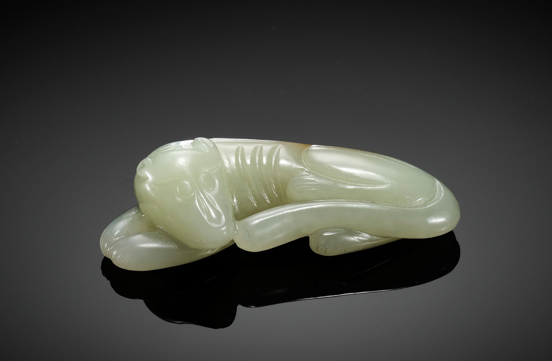 A PALE CELADON JADE CARVING OF A DOG, QING