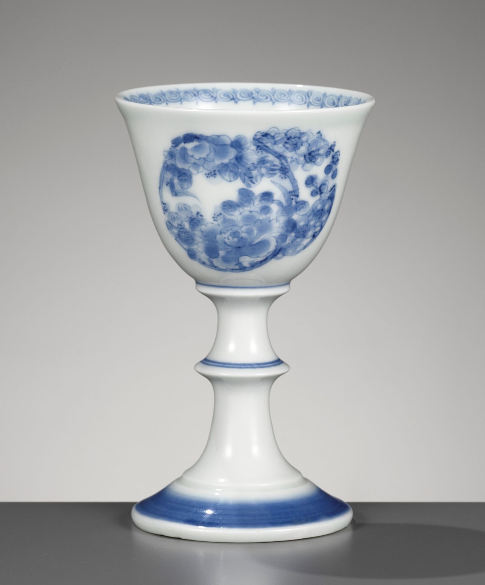 A HIRADO BLUE AND WHITE STEM CUP WITH FLORAL ROUNDELS