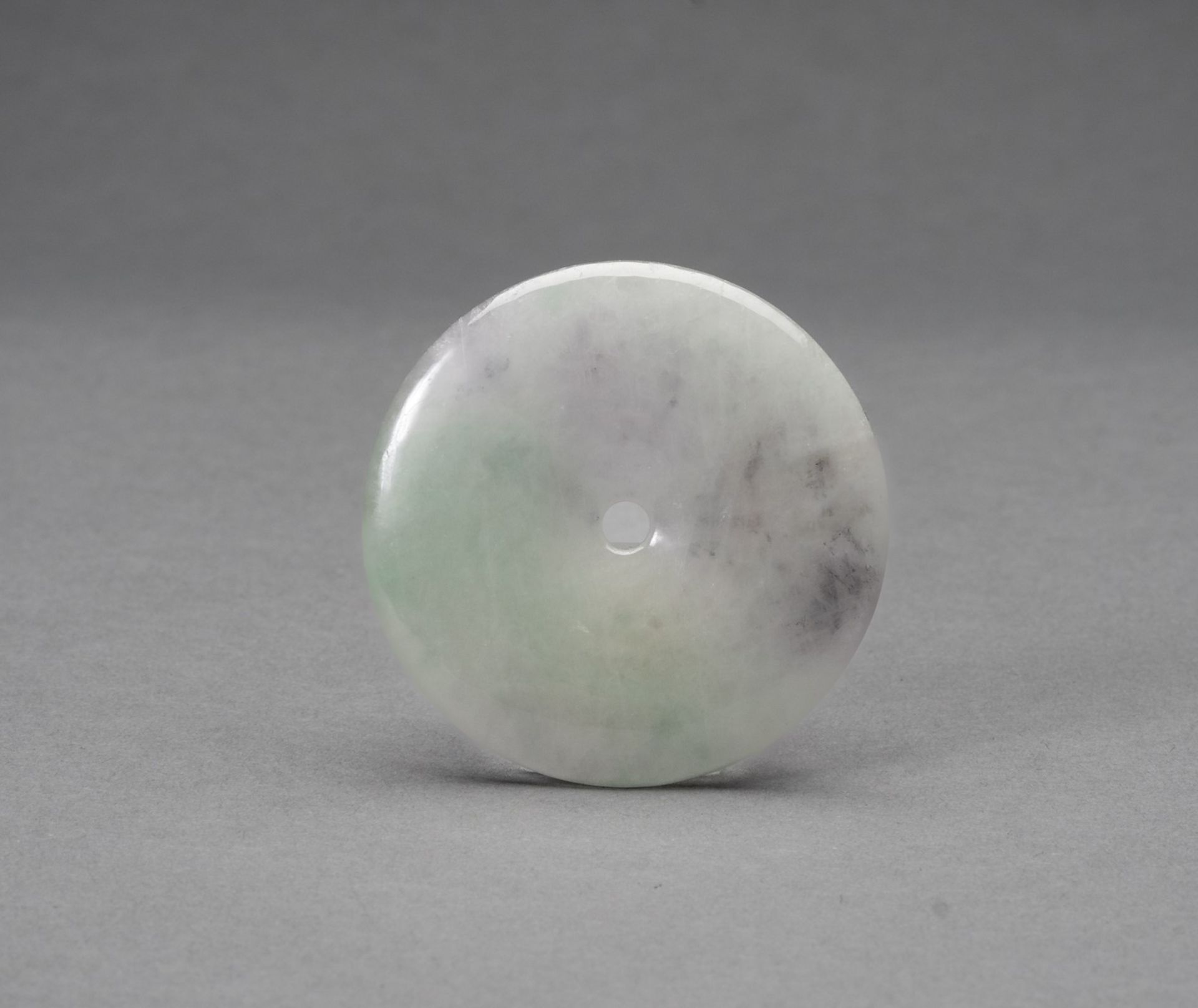 AN ICY HARDSTONE DISC PENDANT