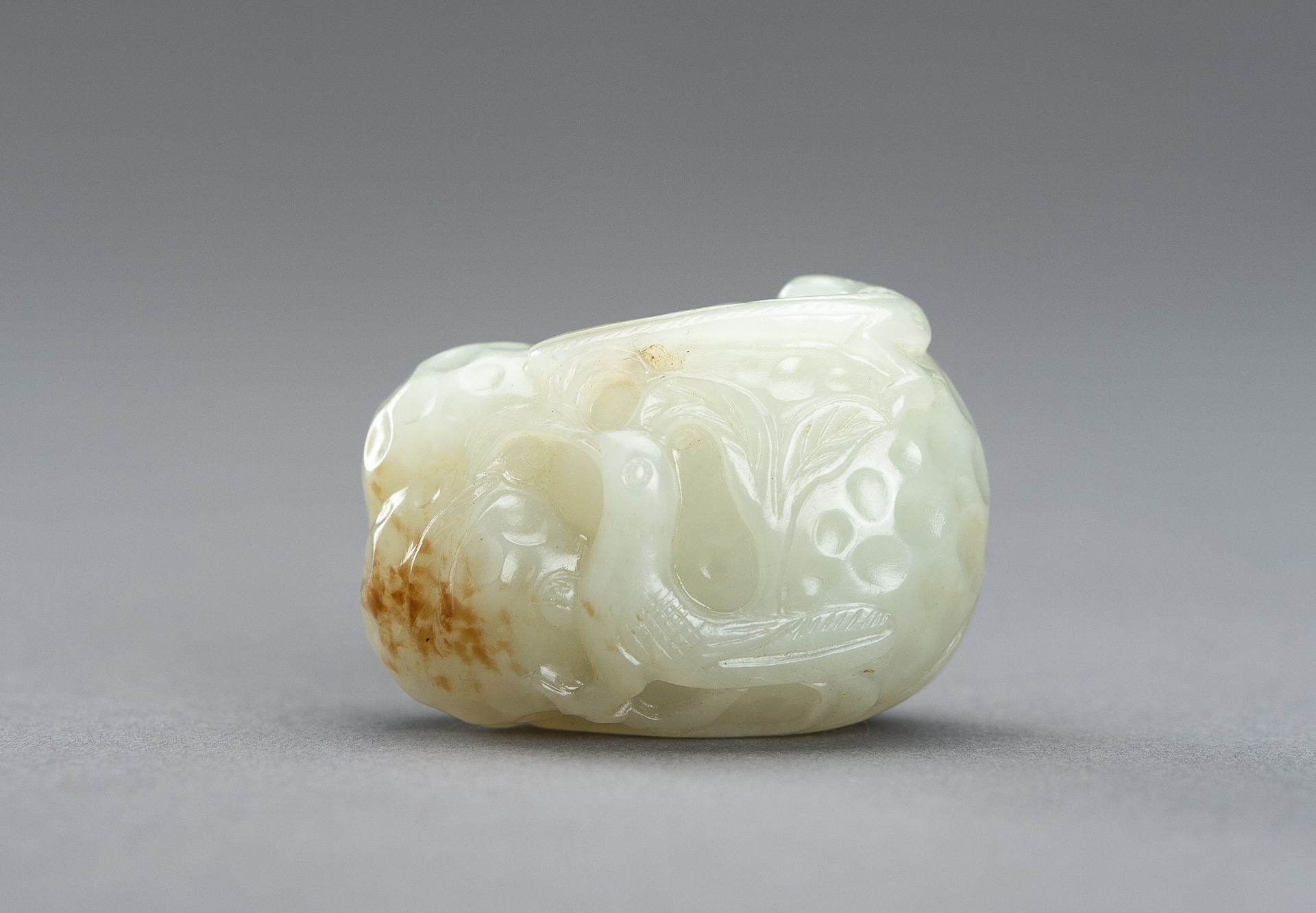 A CELADON JADE PENDANT OF A LYCHEE WITH BIRDS, 1920s