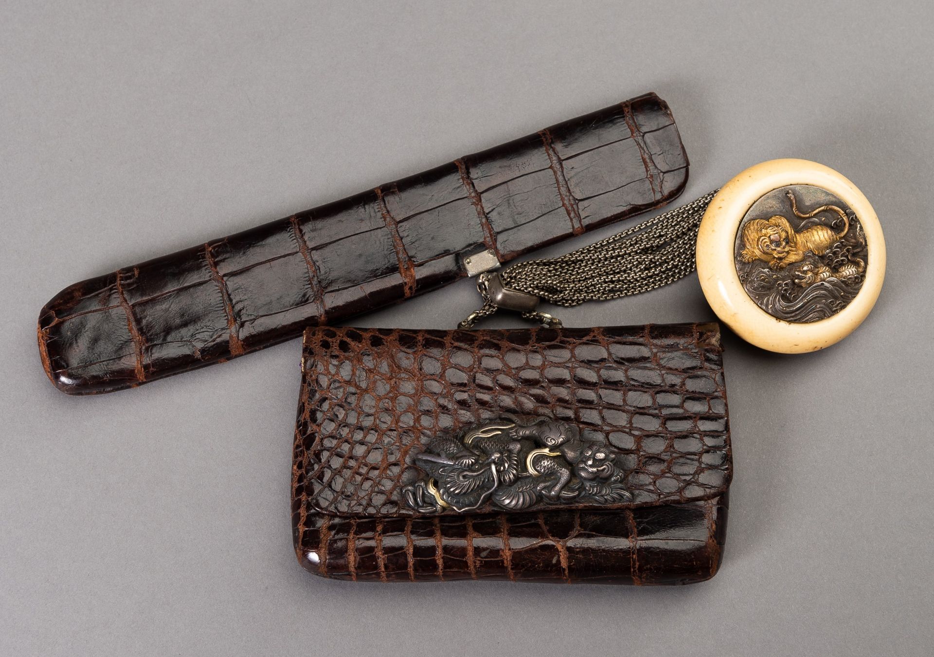 A LEATHER TABAKO-IRE AND ENSEMBLE WITH SILVER-FITTED KAGAMIBUTA NETSUKE DEPICTING A TIGER AND YOUNG