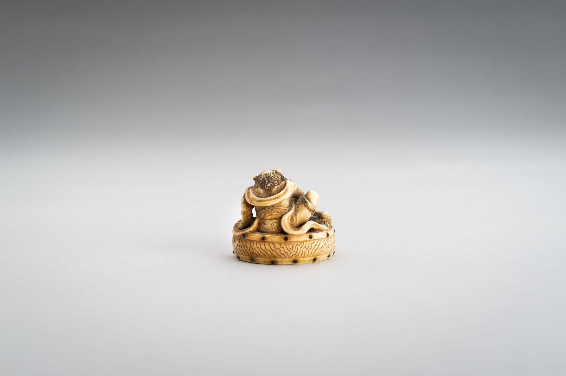 GYOKUSHU: AN IVORY NETSUKE OF AN ONI CLEANING A DRUM - Image 8 of 12