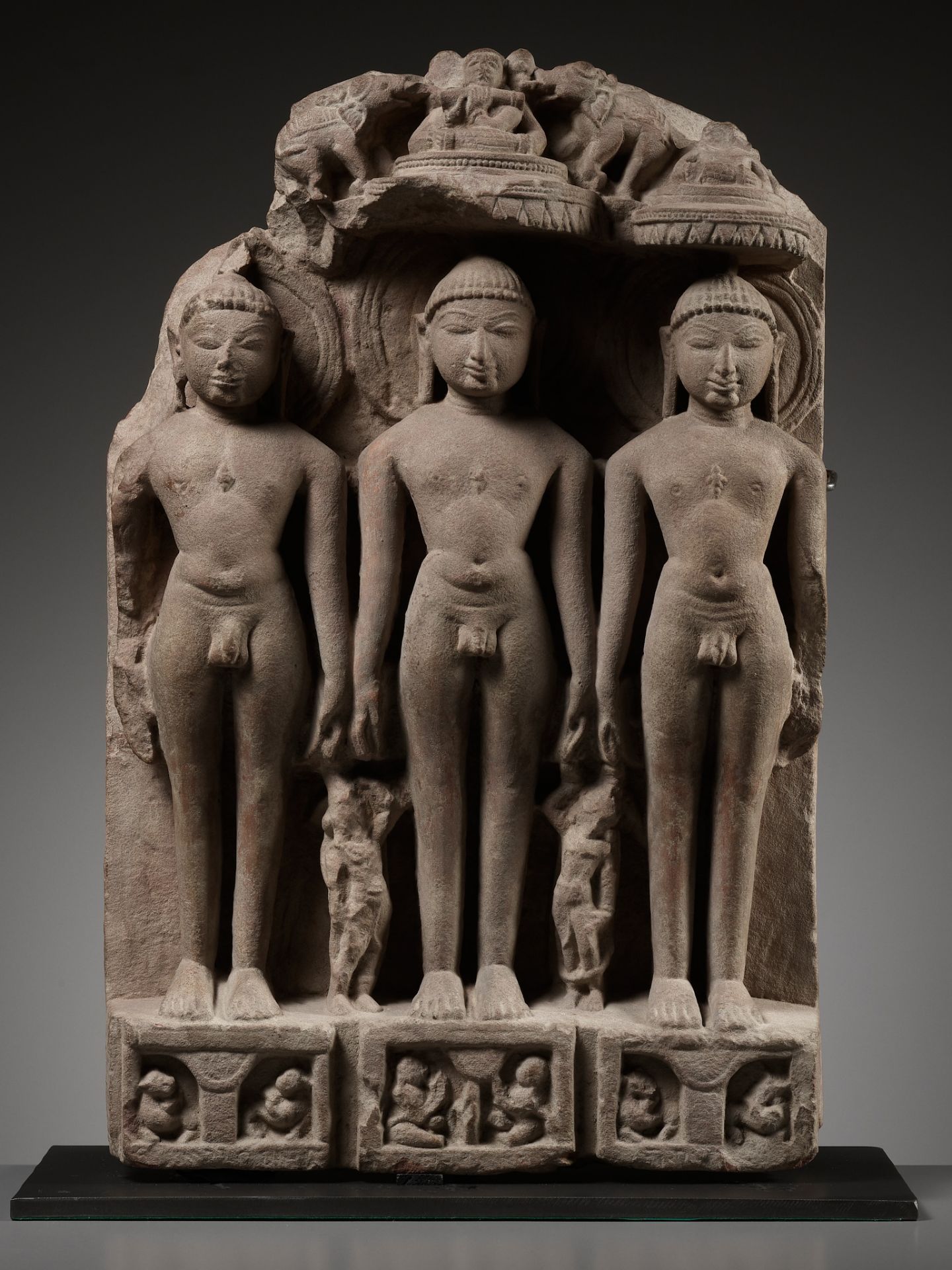 A JAIN SANDSTONE STELE OF THREE JINAS, WESTERN INDIA, RAJASTHAN OR GUJARAT, 10TH-12TH CENTURY