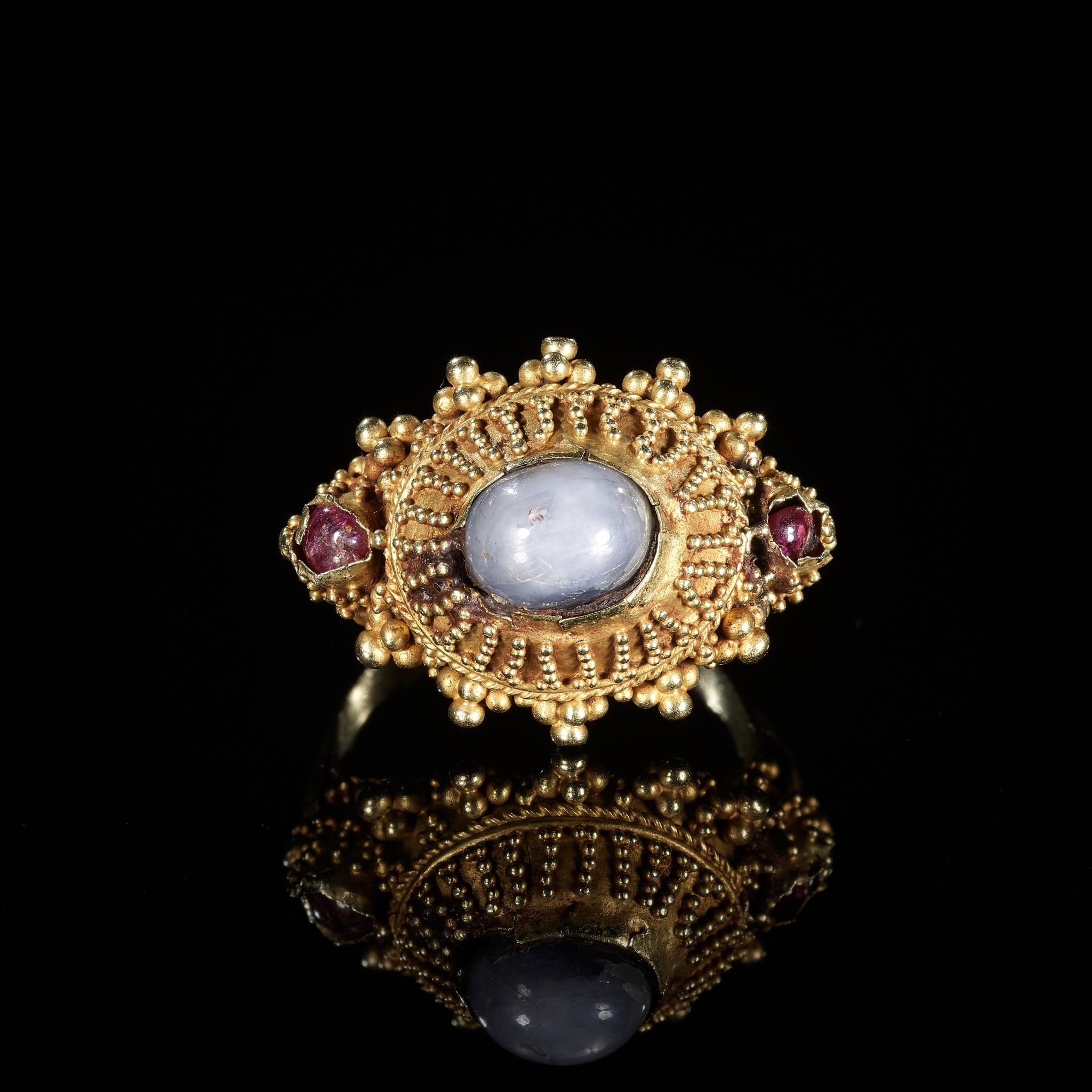 A GOLD PRIEST'S RING INLAID WITH A MOONSTONE AND TWO SMALL GARNETS