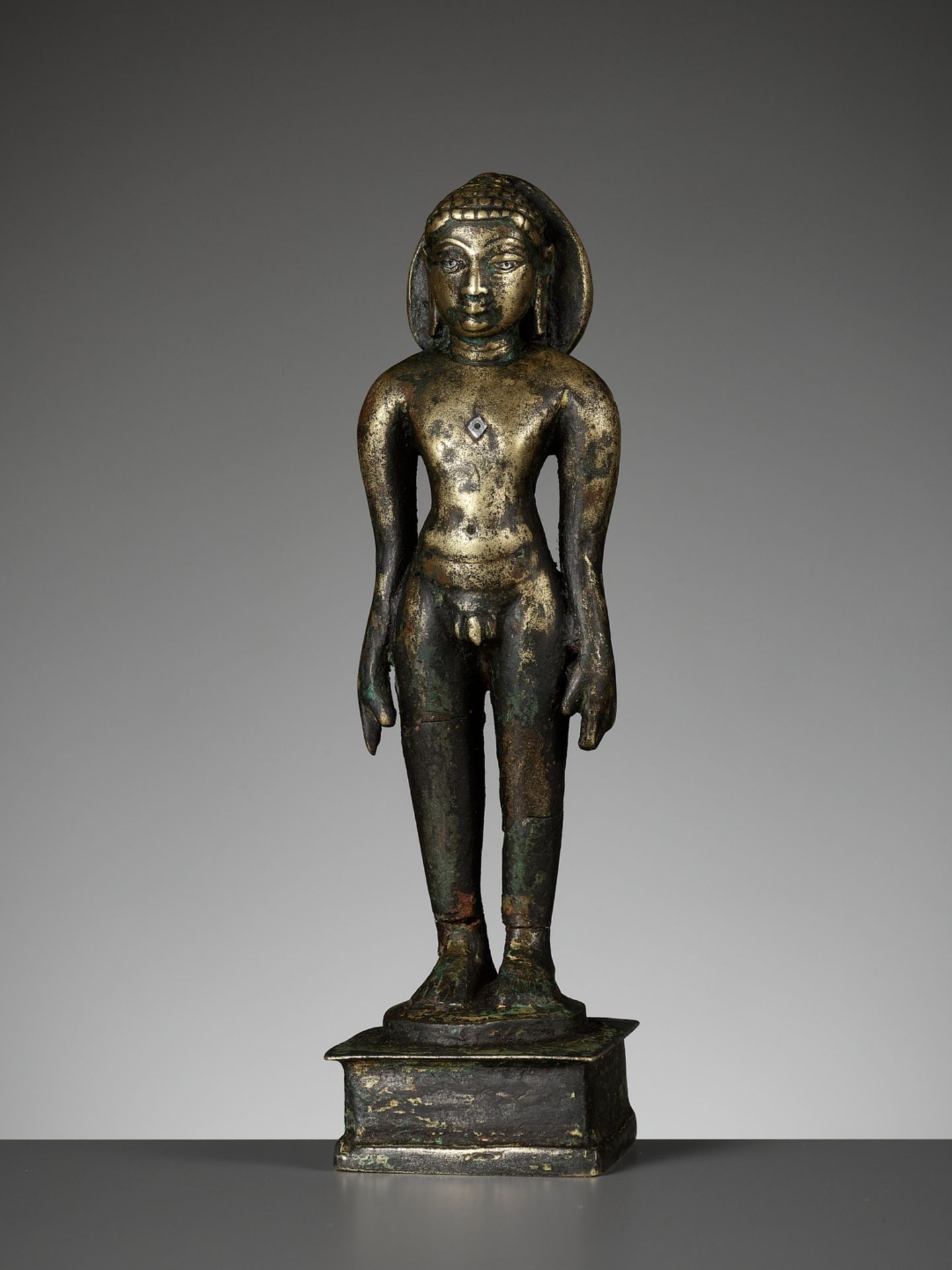 A SILVER-INLAID BRONZE FIGURE OF A JINA, SOUTH INDIA, 10TH - 11TH CENTURY