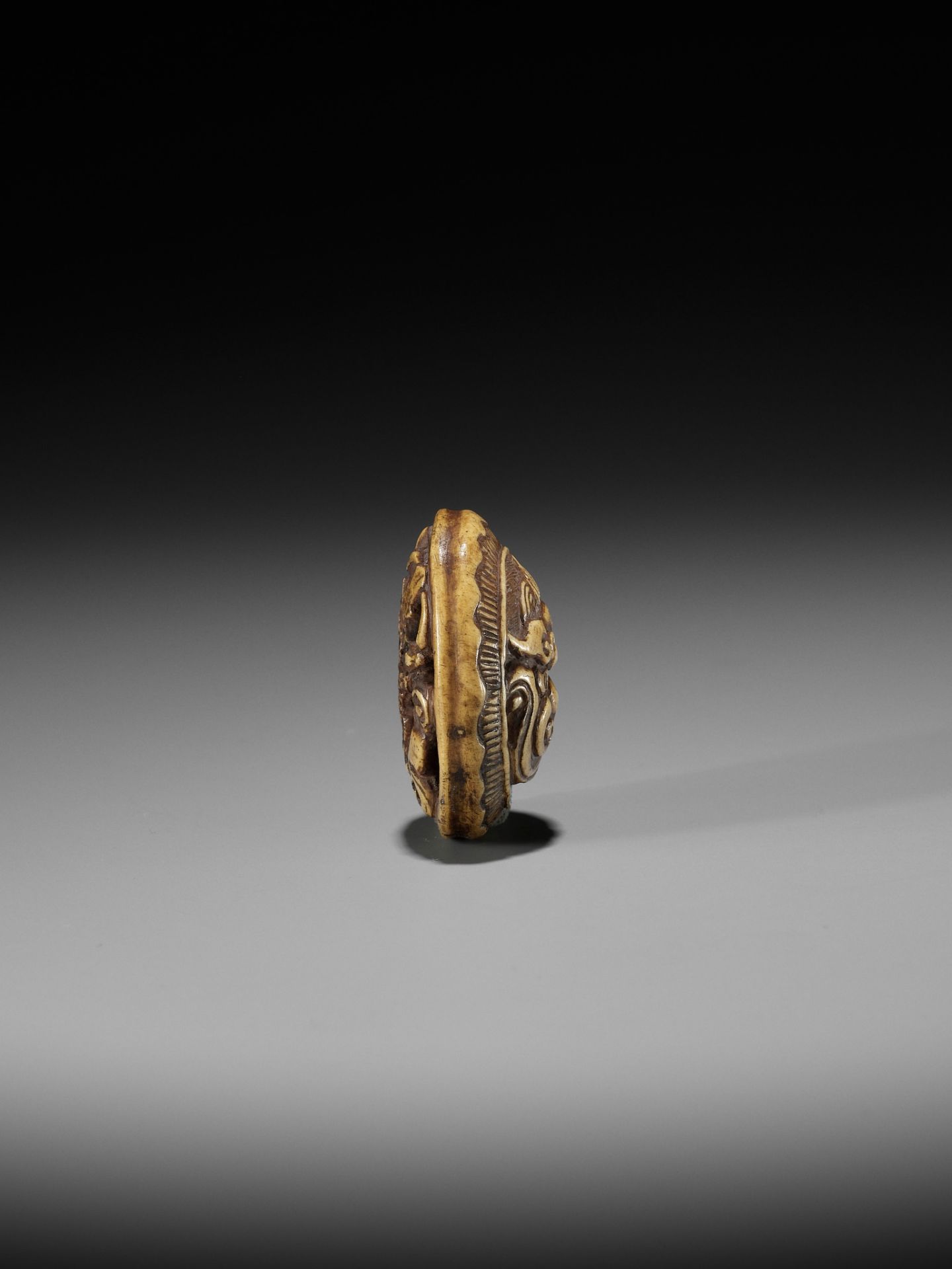 KOKUSAI: A STAG ANTLER RYUSA MANJU NETSUKE DEPICTING A ROOF TILE WITH ONI MASK (ONIGAWARA) - Image 10 of 14