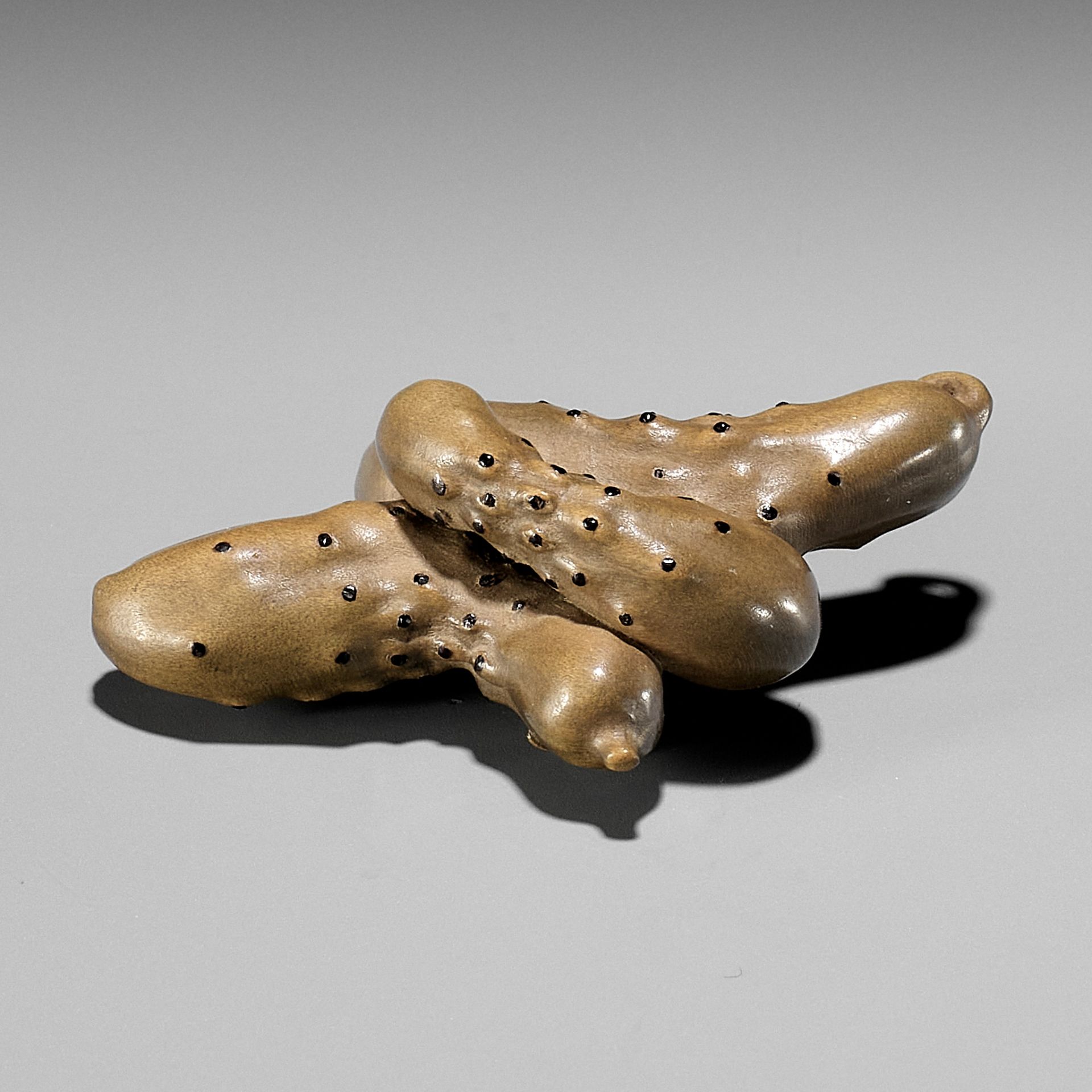 OUCHI GYOKUSO: A MASTERFUL STAINED AND LACQUERED WOOD NETSUKE OF A GROUP OF CUCUMBERS