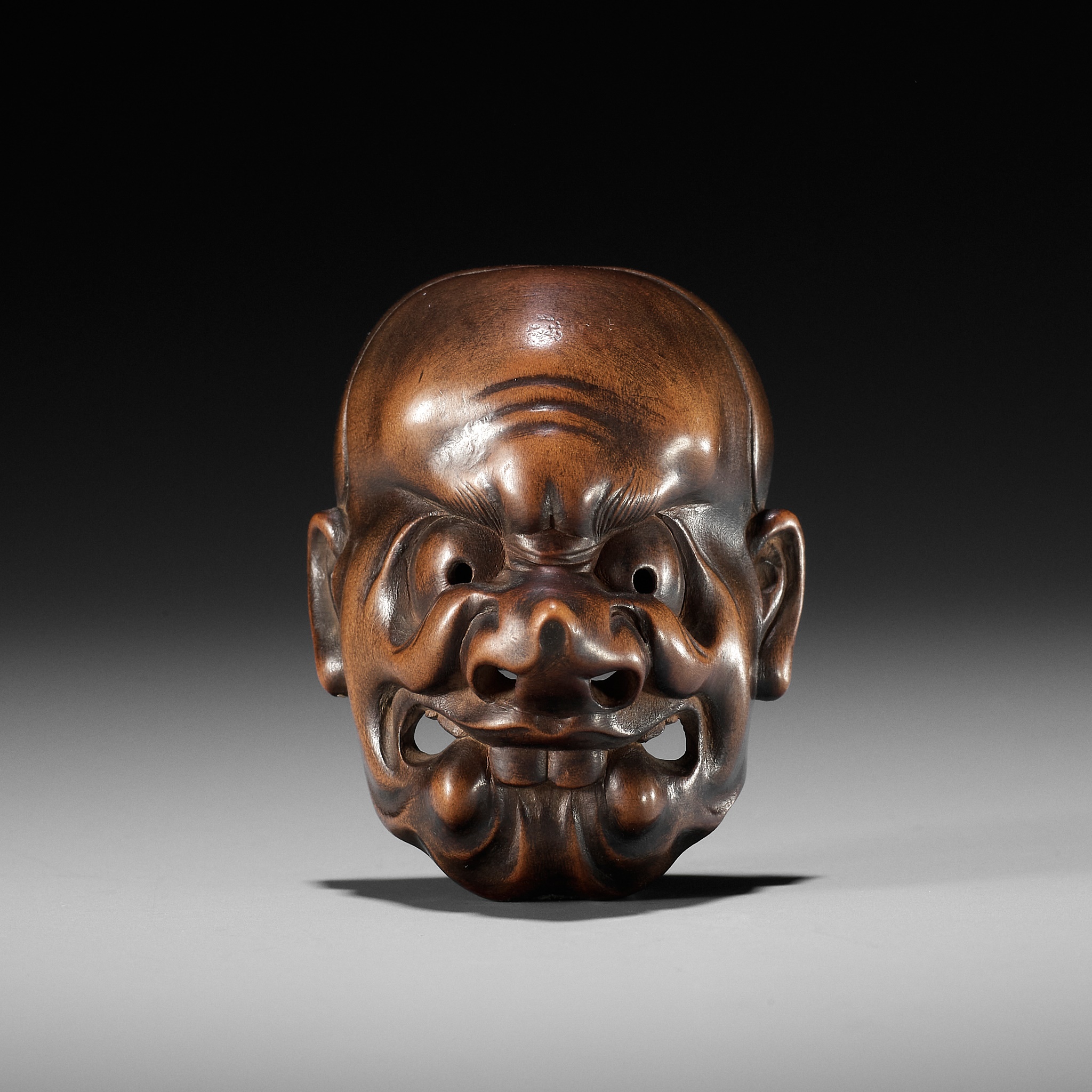 KOKEISAI SANSHO: A SUPERB STAINED WOOD MASK NETSUKE OF A GHOUL