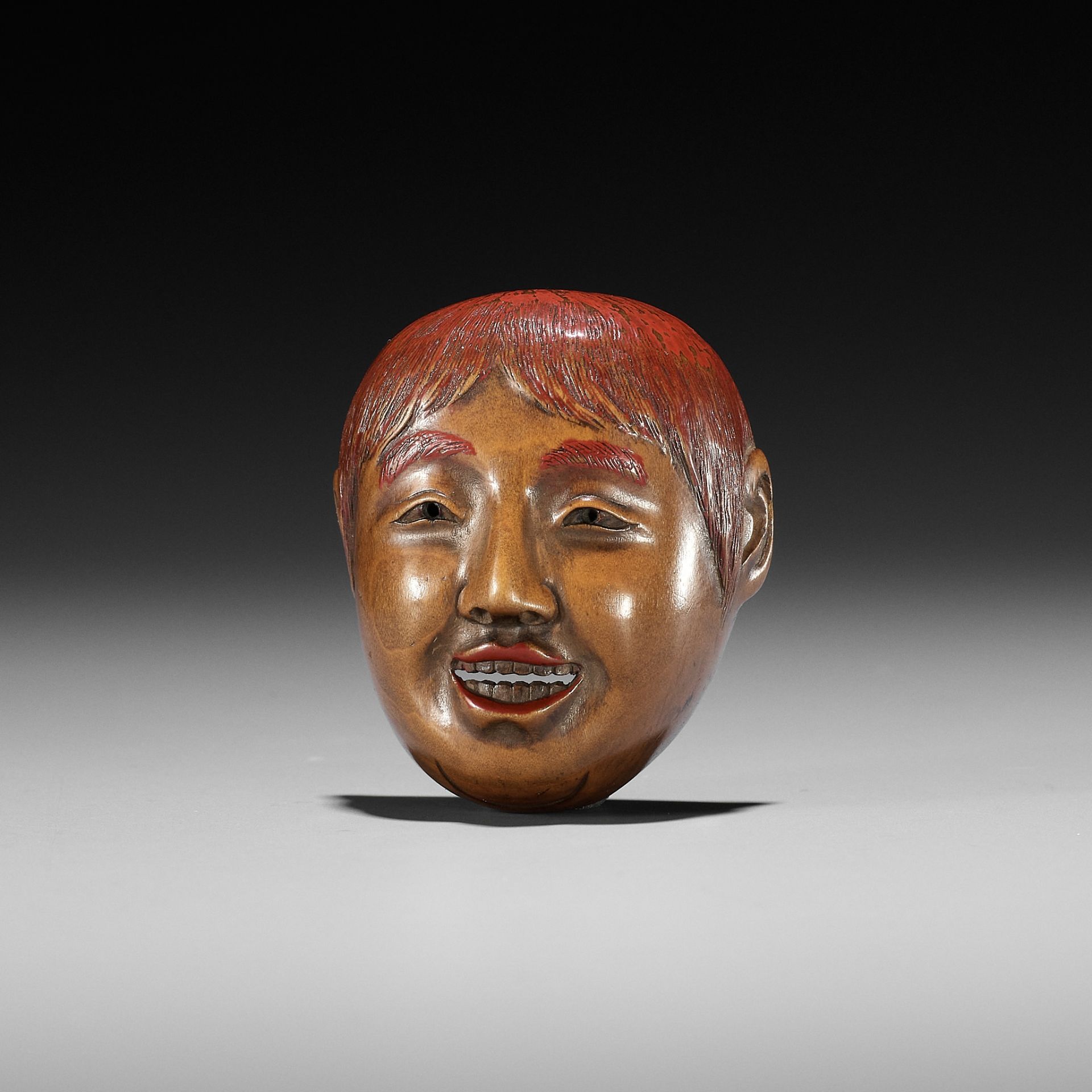 HO RAKUMIN: A WOOD AND LACQUER MASK NETSUKE OF A SHOJO