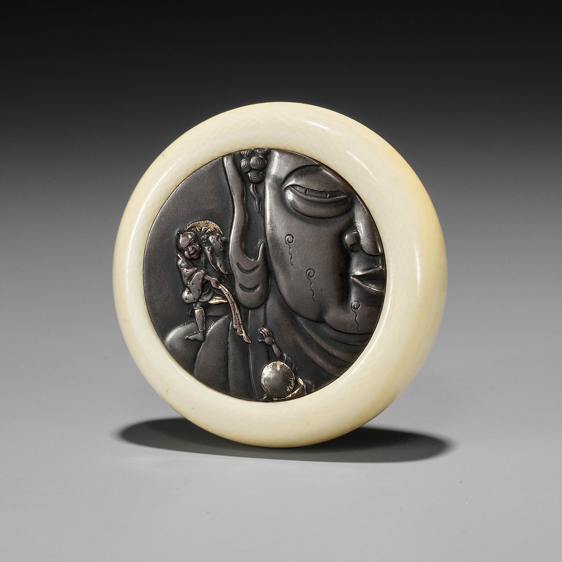 AN IVORY KAGAMIBUTA NETSUKE DEPICTING PILGRIMS CLIMBING THE GREAT BUDDHA OF NARA