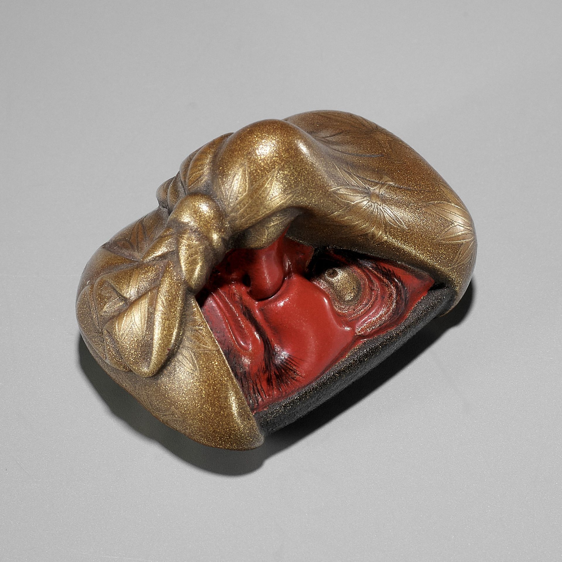 AN EXCEPTIONAL LACQUER NETSUKE OF A KONOHA TENGU MASK WRAPPED IN A FUROSHIKI