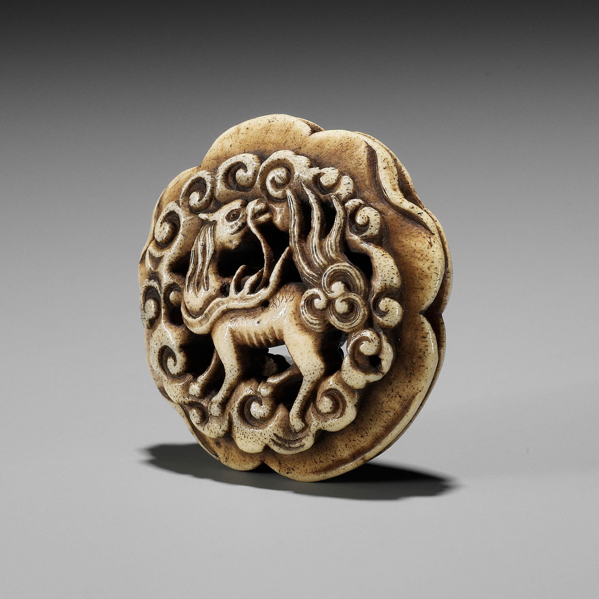 A STAG ANTLER RYUSA MANJU NETSUKE OF A KIRIN AMONGST CLOUDS