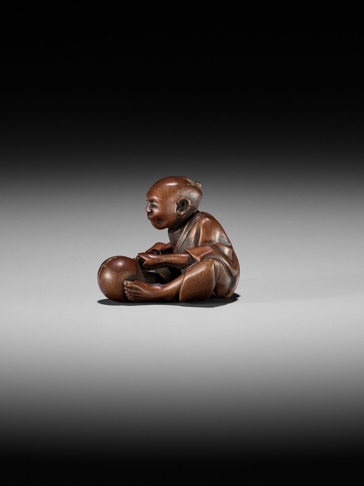 AN AMUSING EDO SCHOOL WOOD SHUNGA NETSUKE OF A MAN CUTTING A HYOTAN - Image 2 of 11