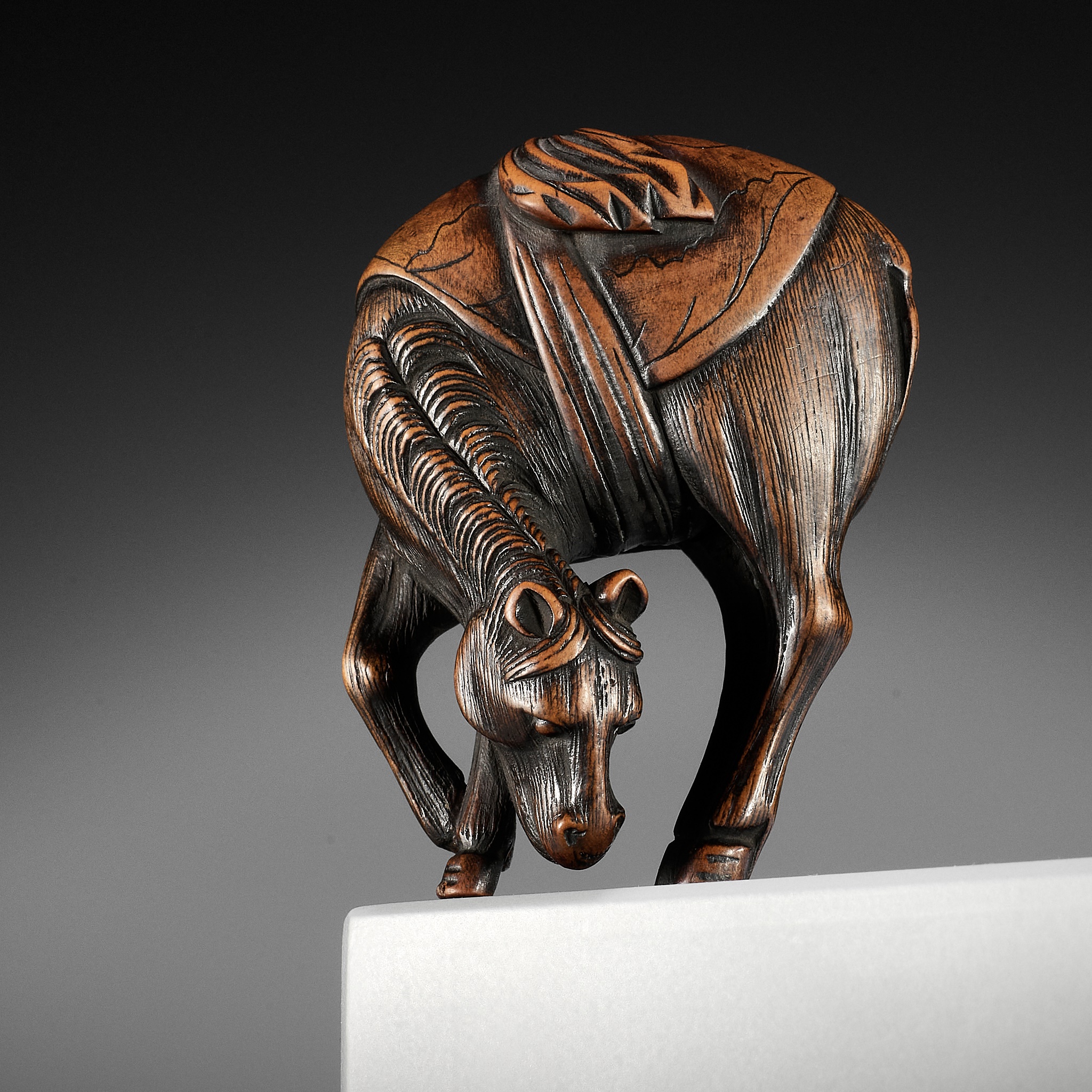 A FINE WOOD NETSUKE OF A GRAZING HORSE