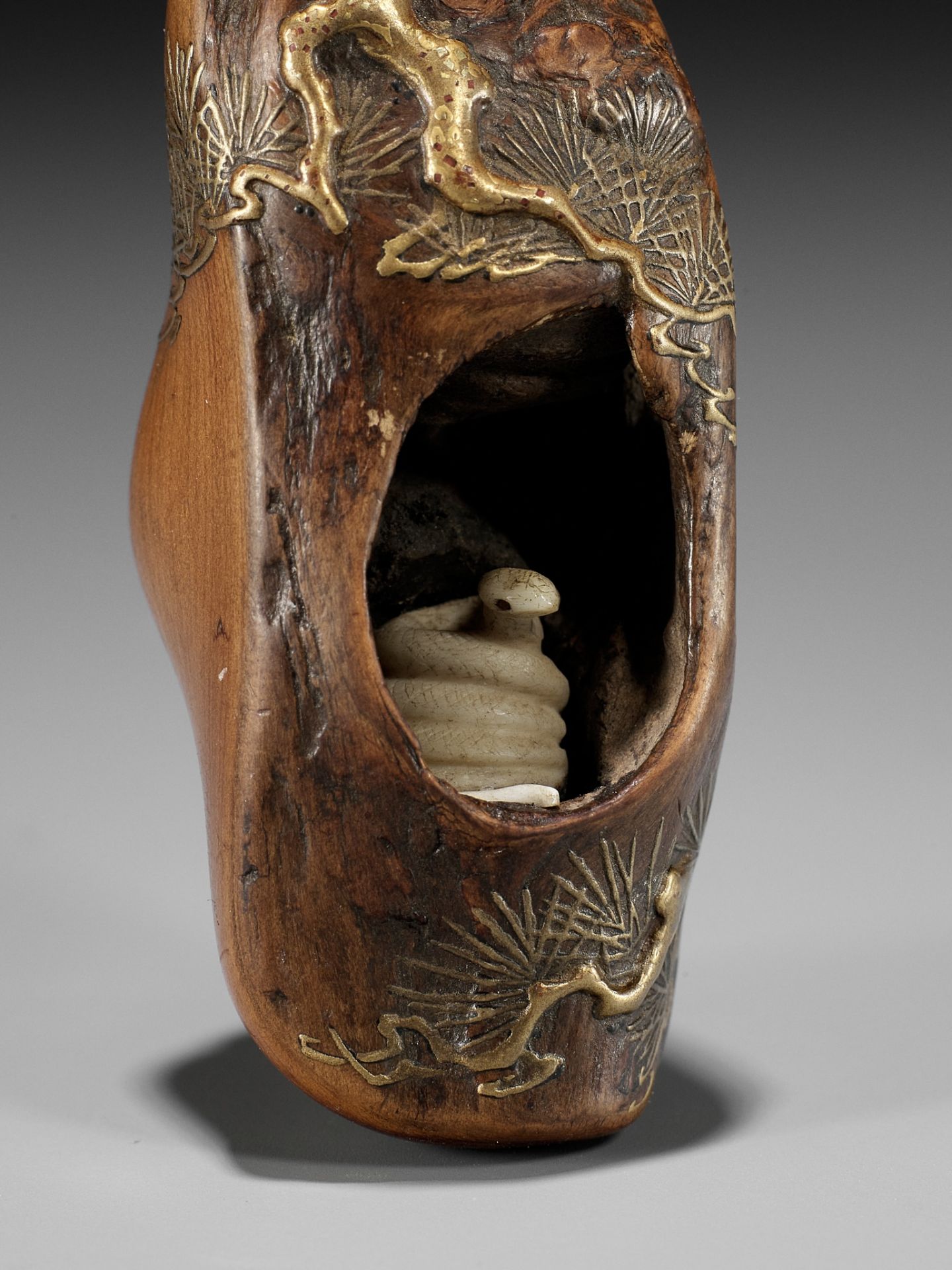 TOYO: A RARE AND UNUSUAL LACQUERED ROOT WOOD NETSUKE OF A SNAKE INSIDE A PINE TREE