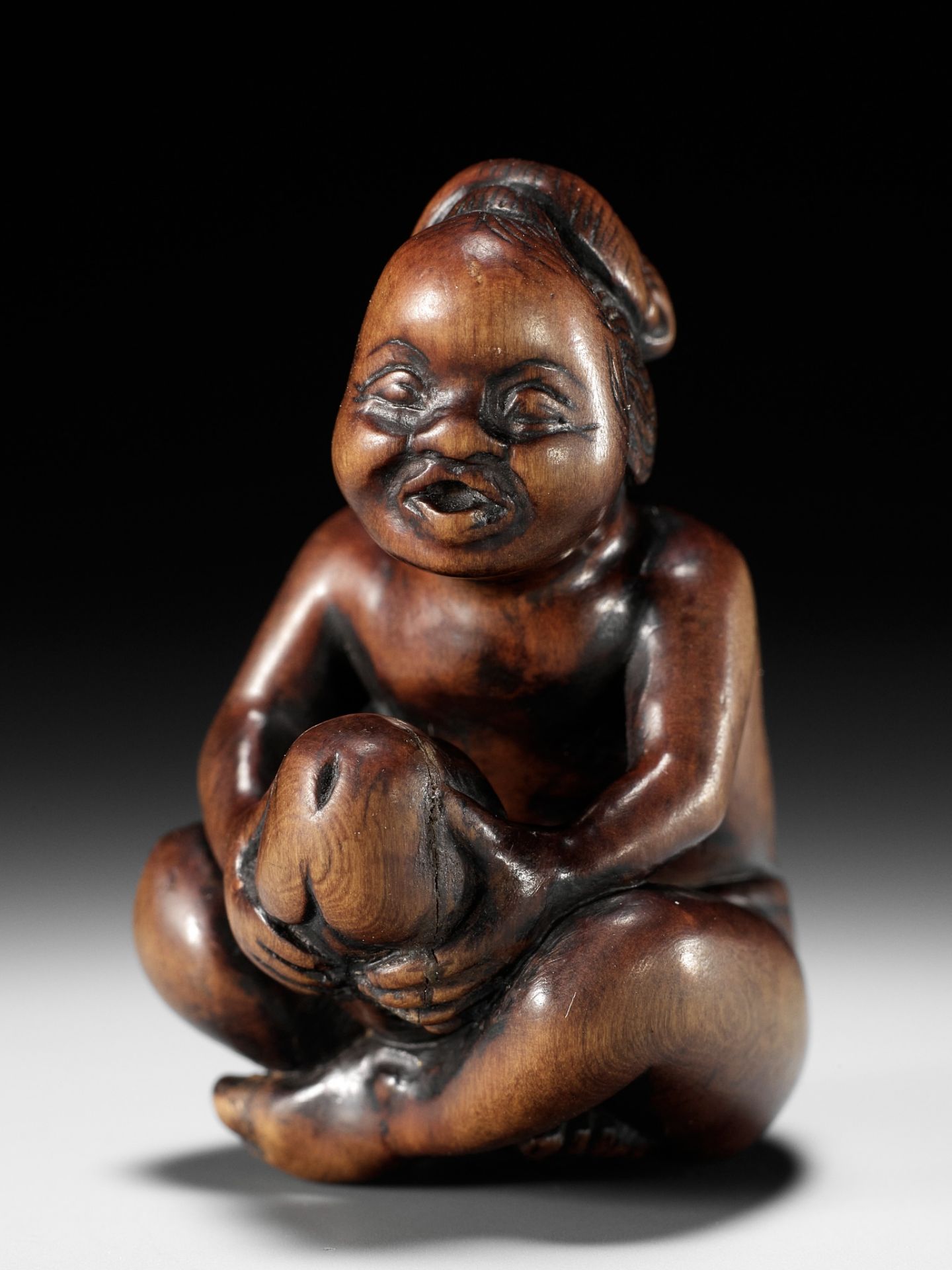 A SUPERB WOOD SHUNGA NETSUKE OF A MAN WITH OKAME MASK