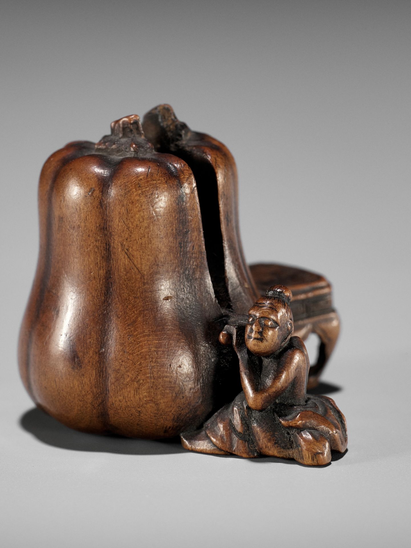 NAOYUKI: AN EXQUISITE MINIATURE WOOD NETSUKE OF A NIO CUTTING THROUGH A GIGANTIC GOURD