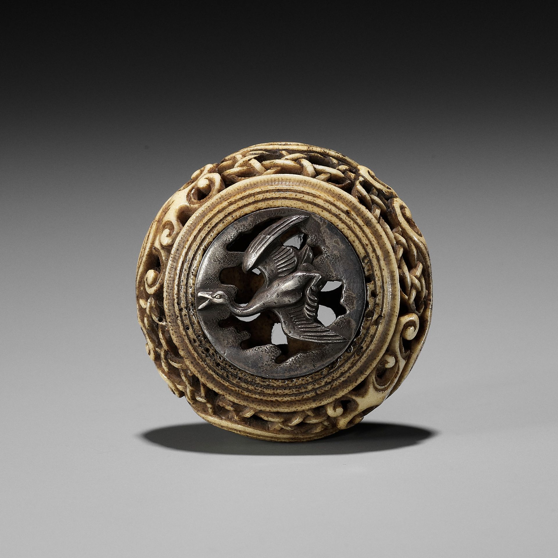 A STAG ANTLER AND SHIBUICHI KAGAMIBUTA NETSUKE DEPICTING A GOOSE IN FLIGHT