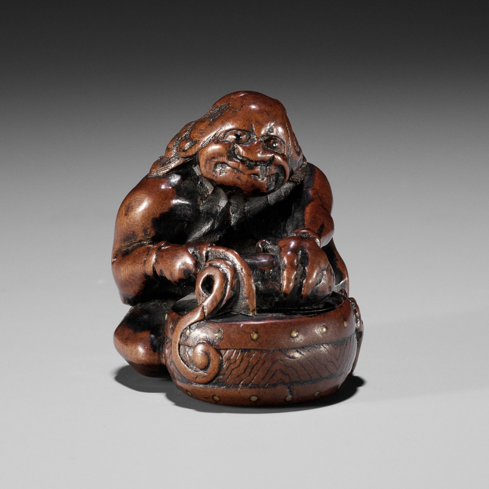 GYOKUMIN: A FINE AND RARE NAGOYA SCHOOL WOOD NETSUKE OF RAIJIN CUTTING A CUCUMBER