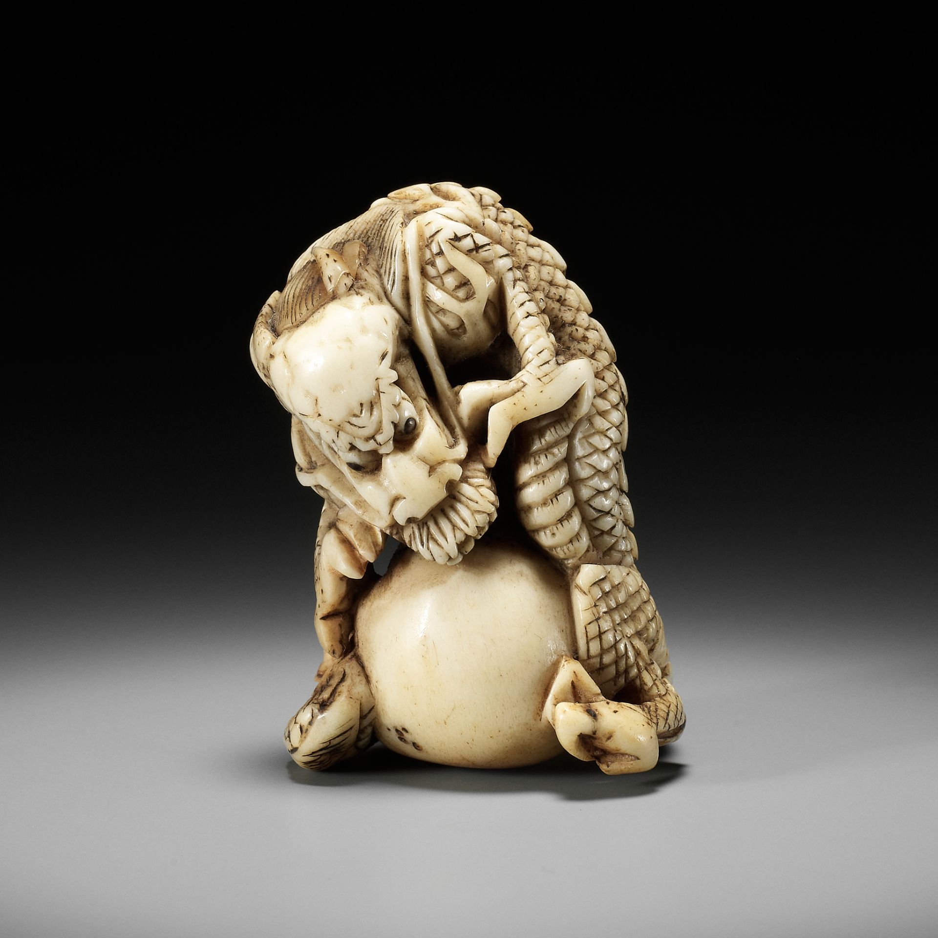 A POWERFUL STAG ANTLER NETSUKE OF A DRAGON WITH TAMA, ATTRIBUTED TO MOTOTADA