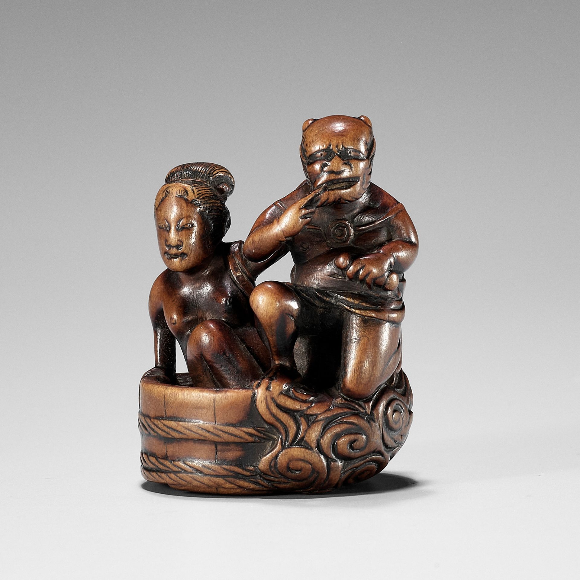 HOMIN: A GOOD WOOD NETSUKE OF RAIJIN WITH BATHING WOMAN