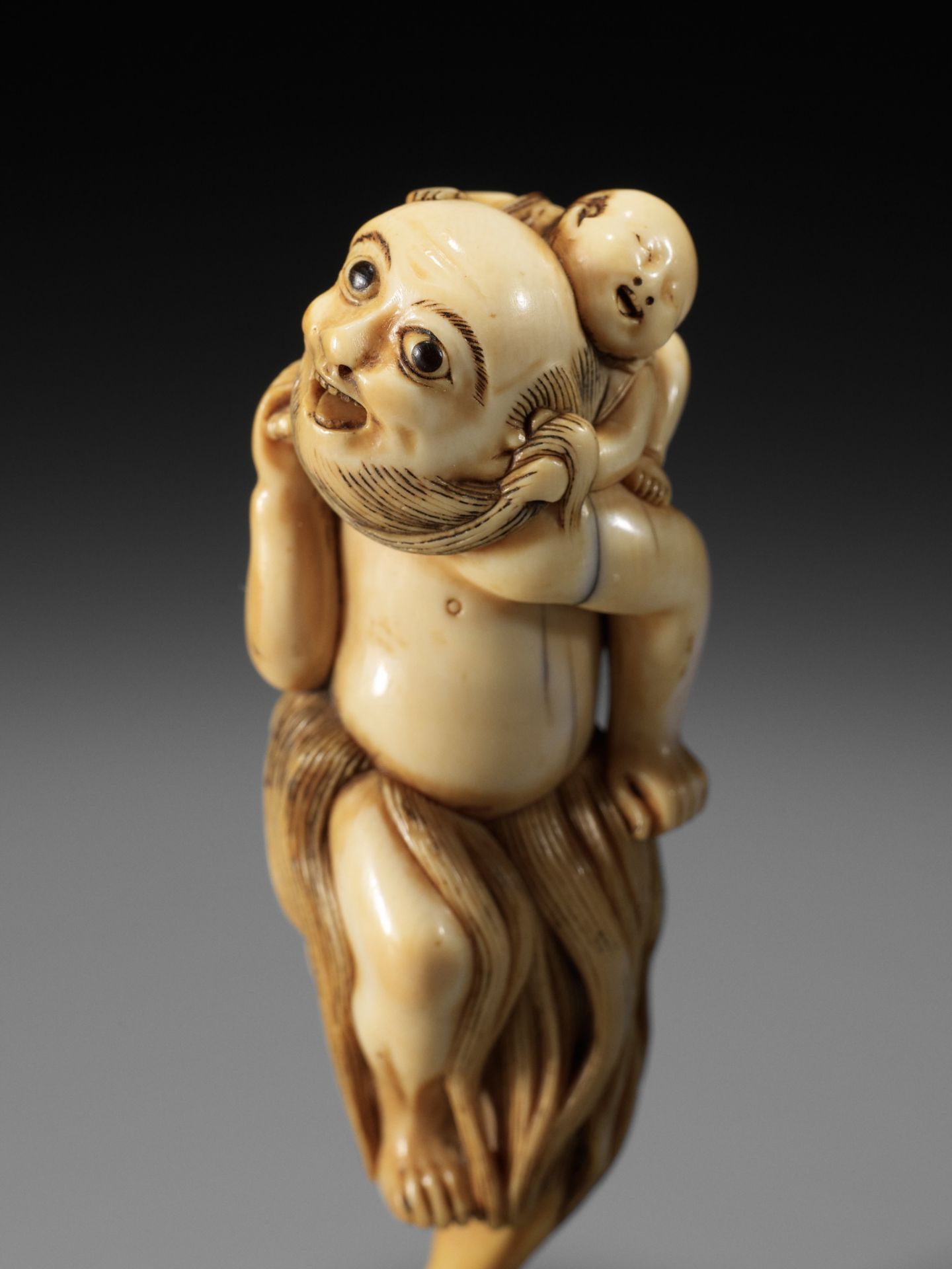 A SUPERB IVORY NETSUKE OF A FISHERMAN CARRYING A BOY, ATTRIBUTED TO GECHU