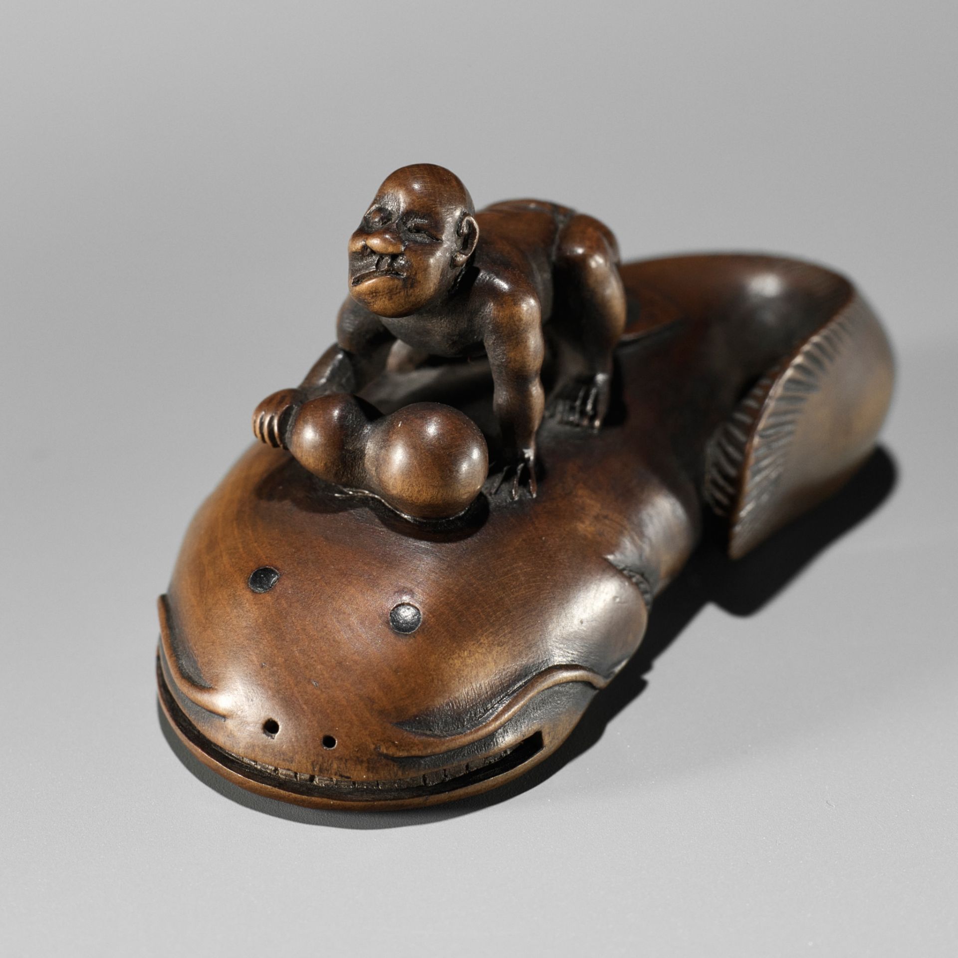 MUGAI: A RARE WOOD NETSUKE OF A BLIND FISHERMAN TAMING THE NAMAZU