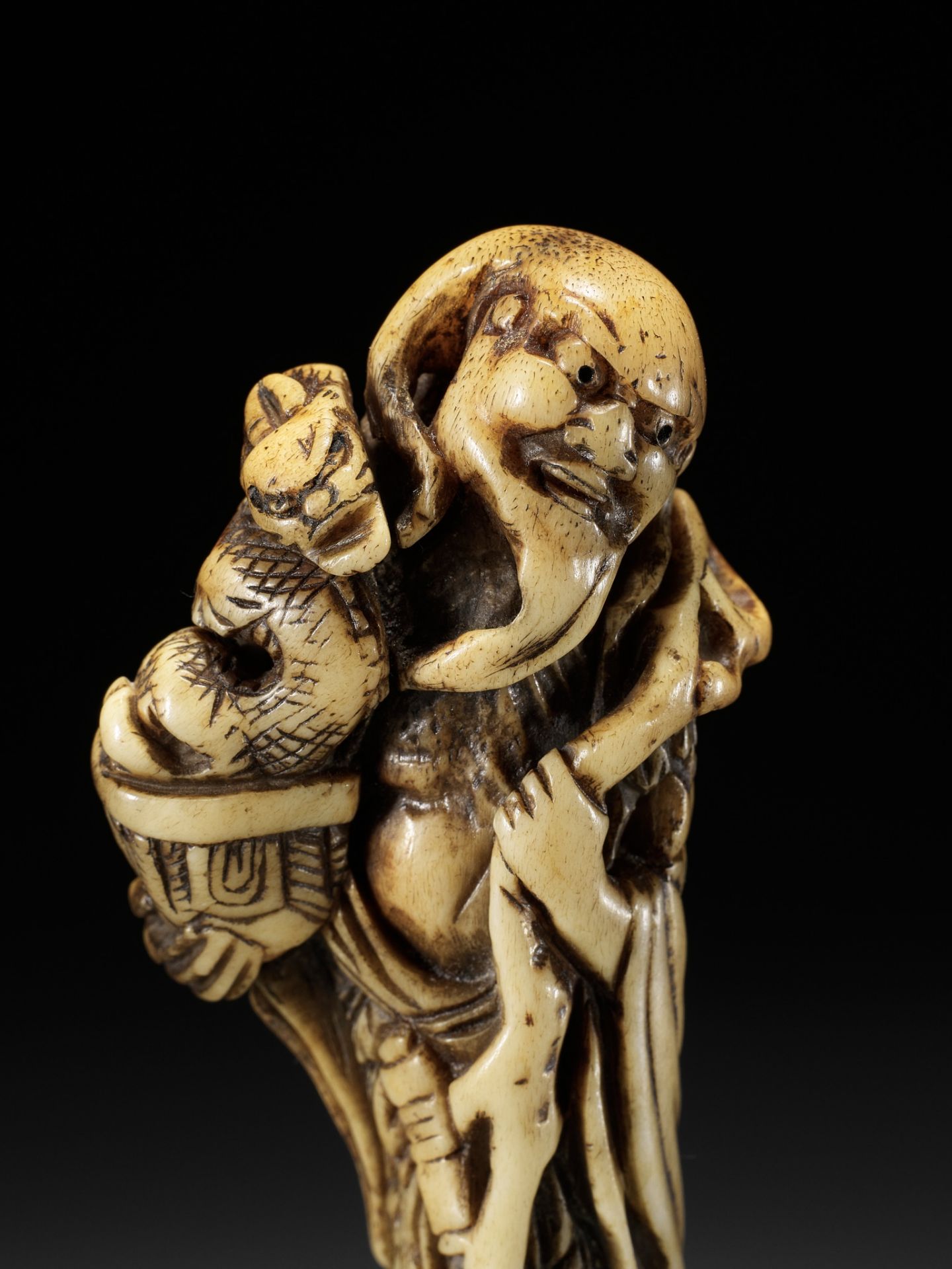 A POWERFUL TALL STAG ANTLER NETSUKE OF CHINNAN SENNIN, ATTRIBUTED TO TOMOHISA