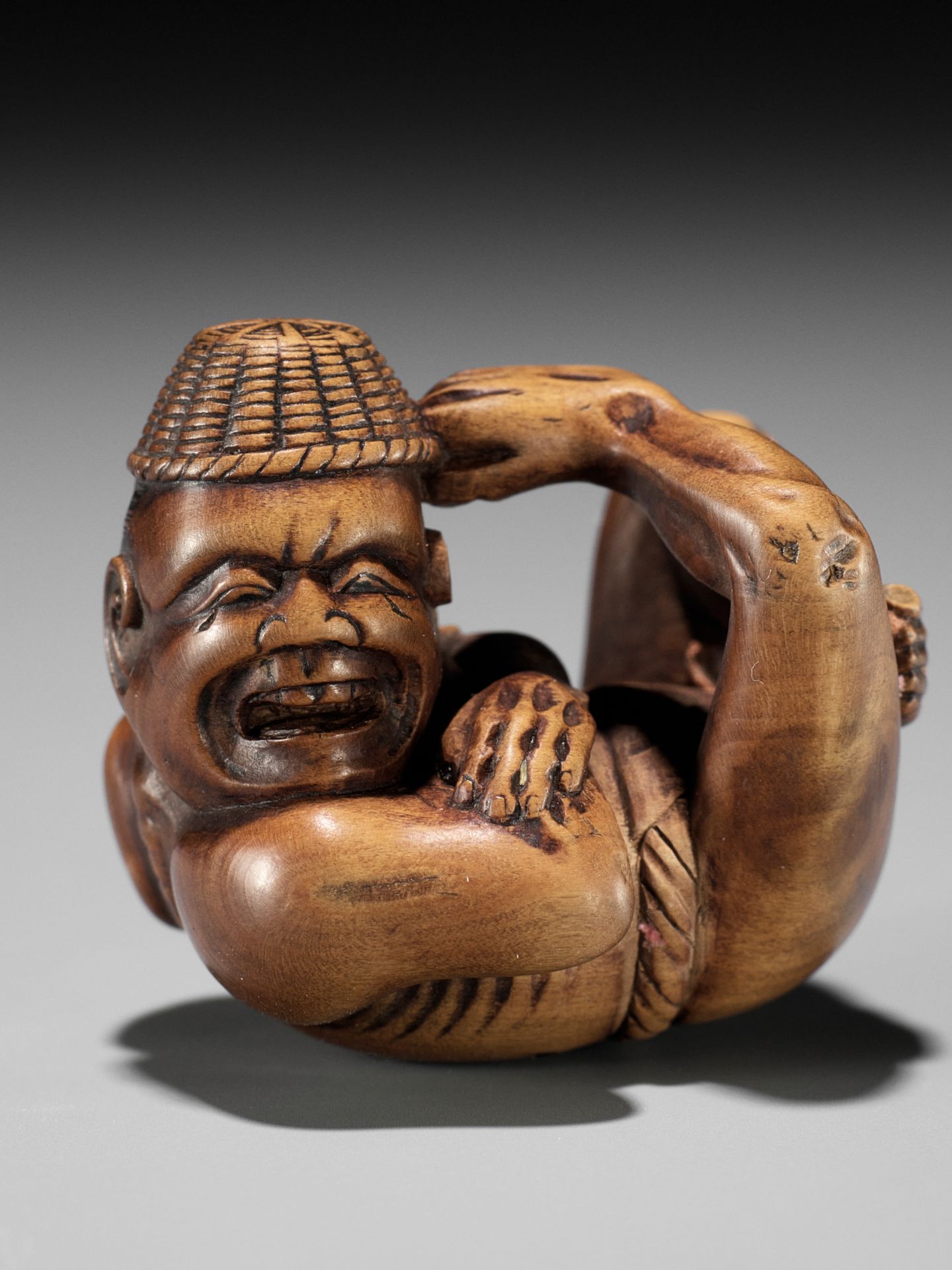 AN AMUSING EDO SCHOOL WOOD NETSUKE OF A MOXA CONTORTIONIST