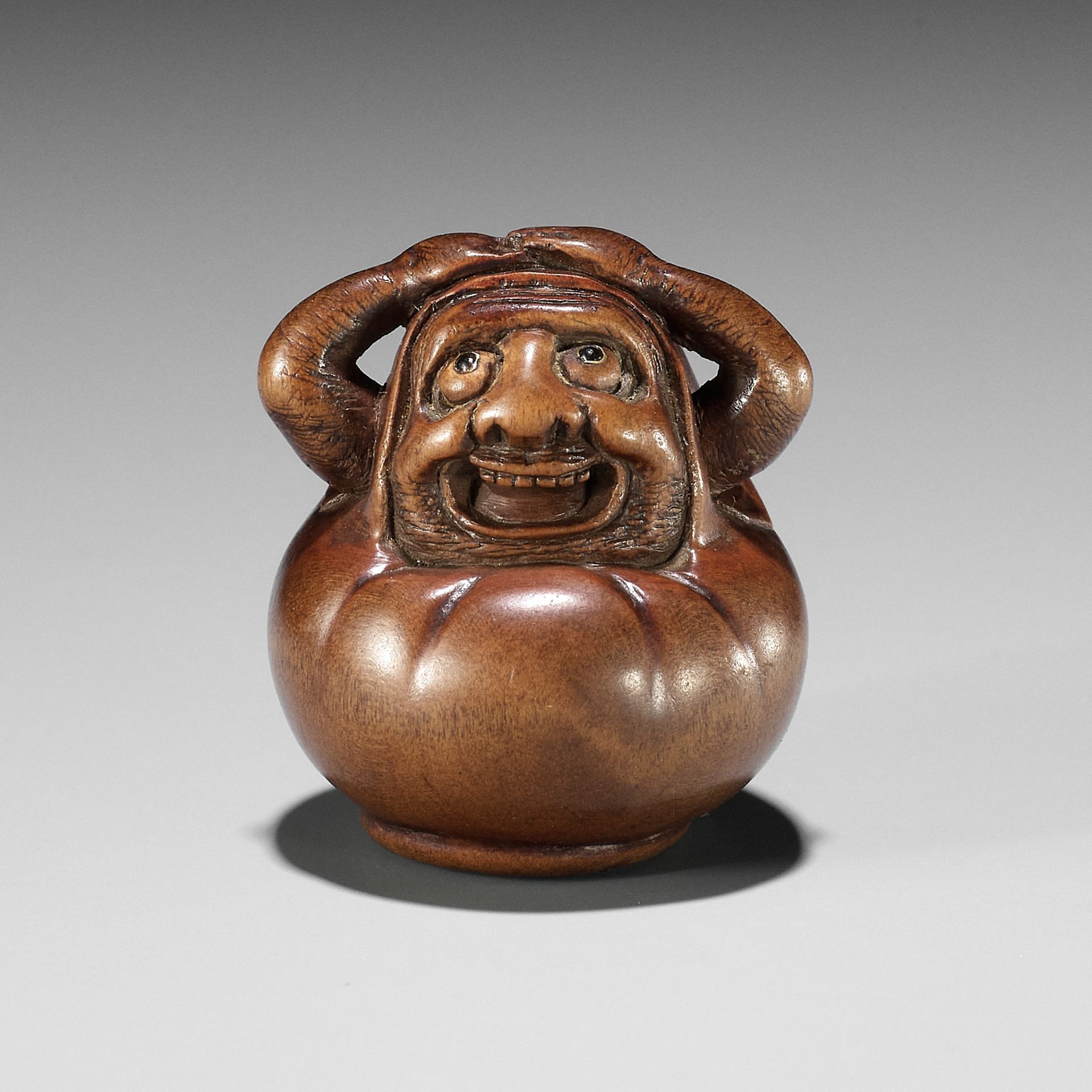 HIDARI ISSAN: A CHARMING WOOD NETSUKE OF A DARUMA DOLL